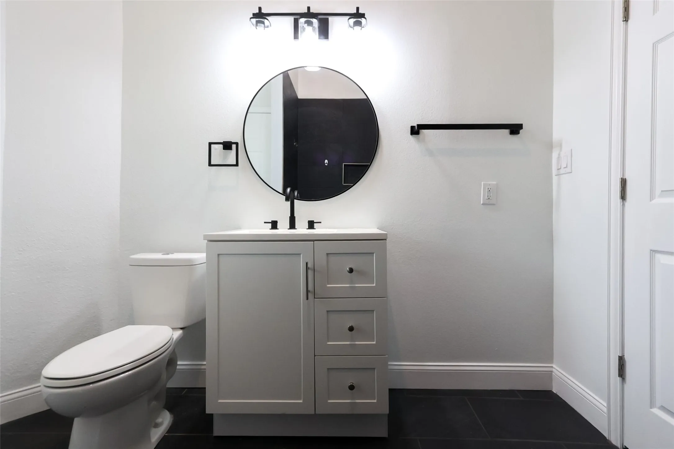 Vanity with ample storage, dark hardware, and a matching circular mirror