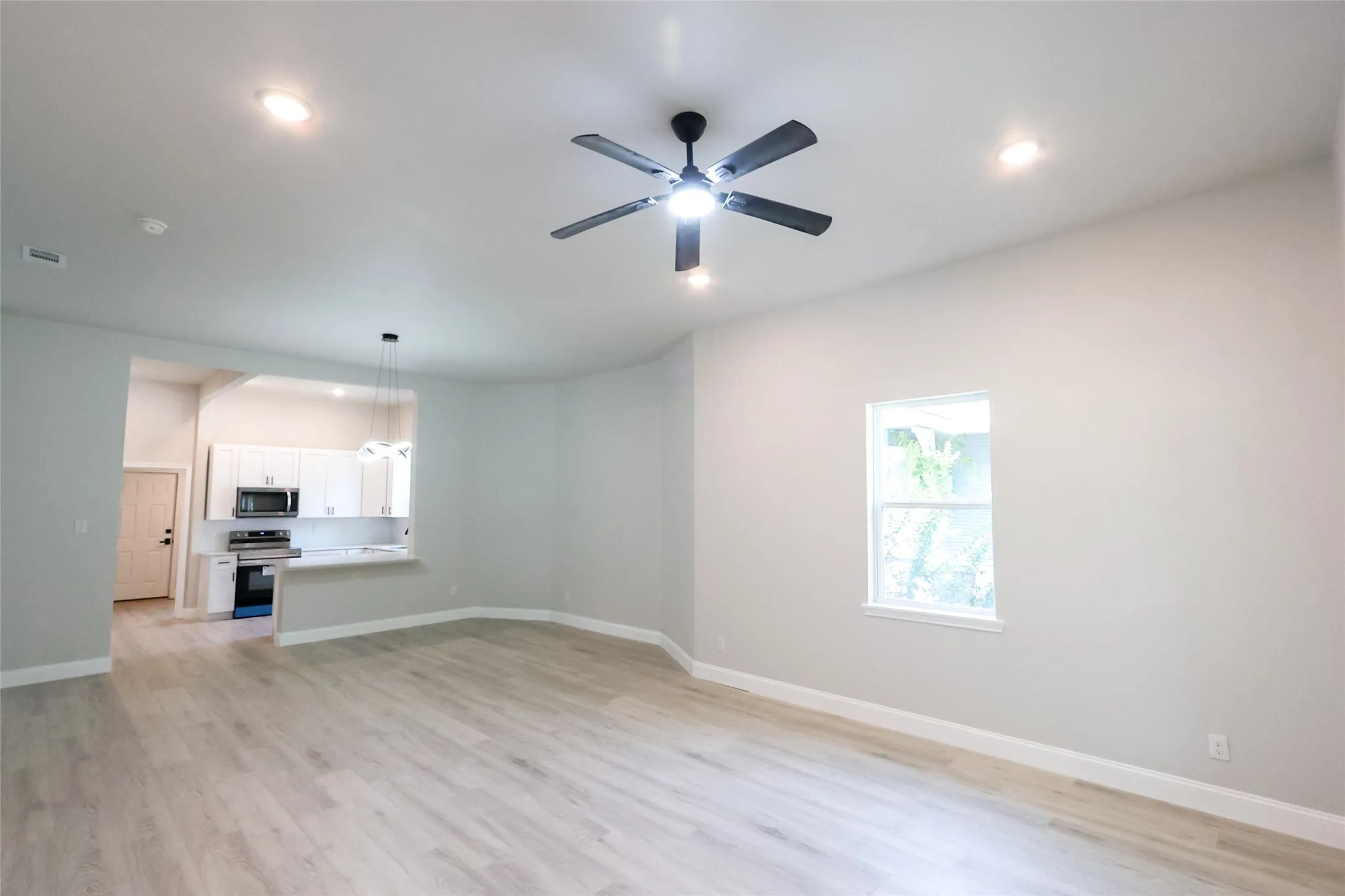 Light wood-finish flooring, recessed lighting, and a ceiling fan in the living area