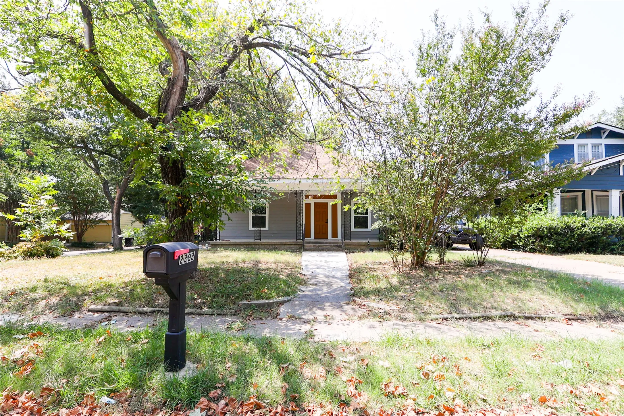 Craftsman-style home with a covered front porch, a light grey exterior, and a prominent wood-finish front door