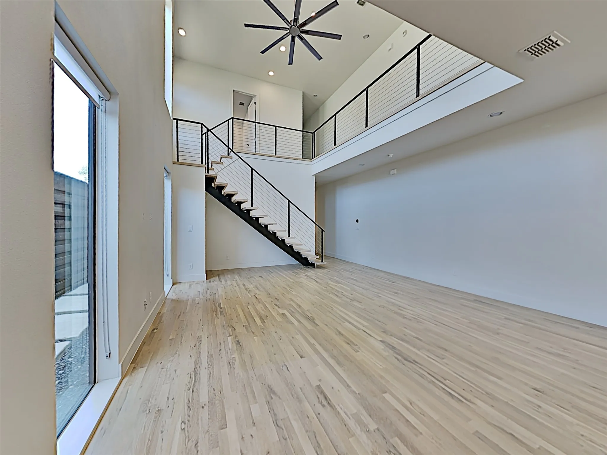 2 story living area with white oak floors, commercial size ceiling fan.