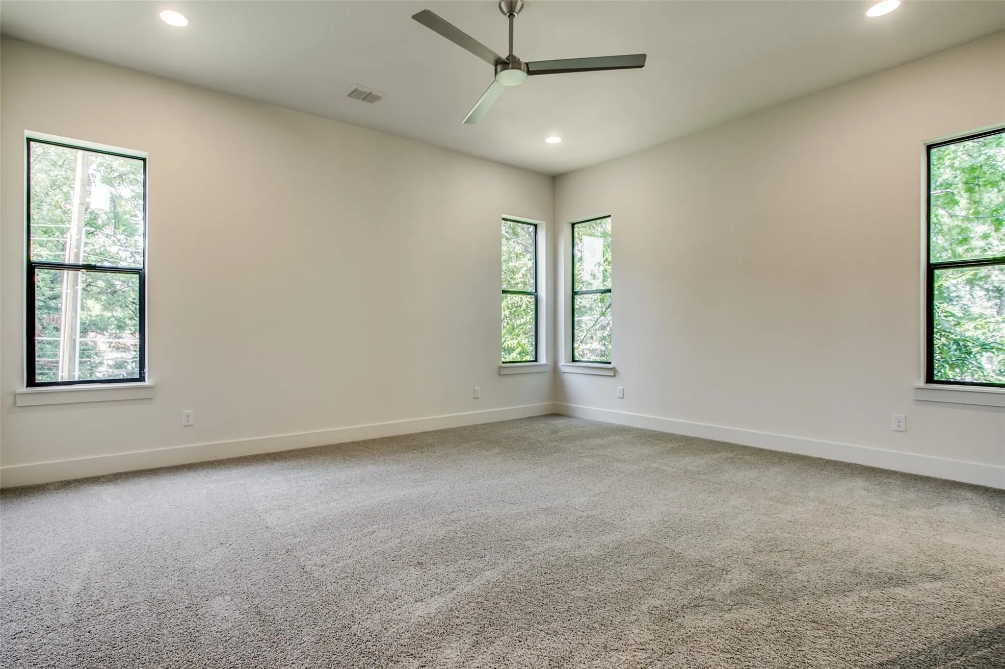 Spacious primary bedroom with high ceilings and natural light.