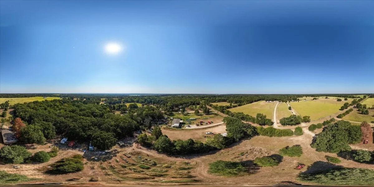 Expansive rural landscape featuring wooded areas and open fields
