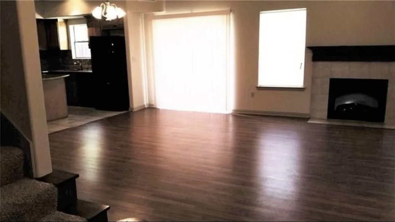 Wood-finish flooring throughout, a tiled fireplace with mantel, and a sliding glass door