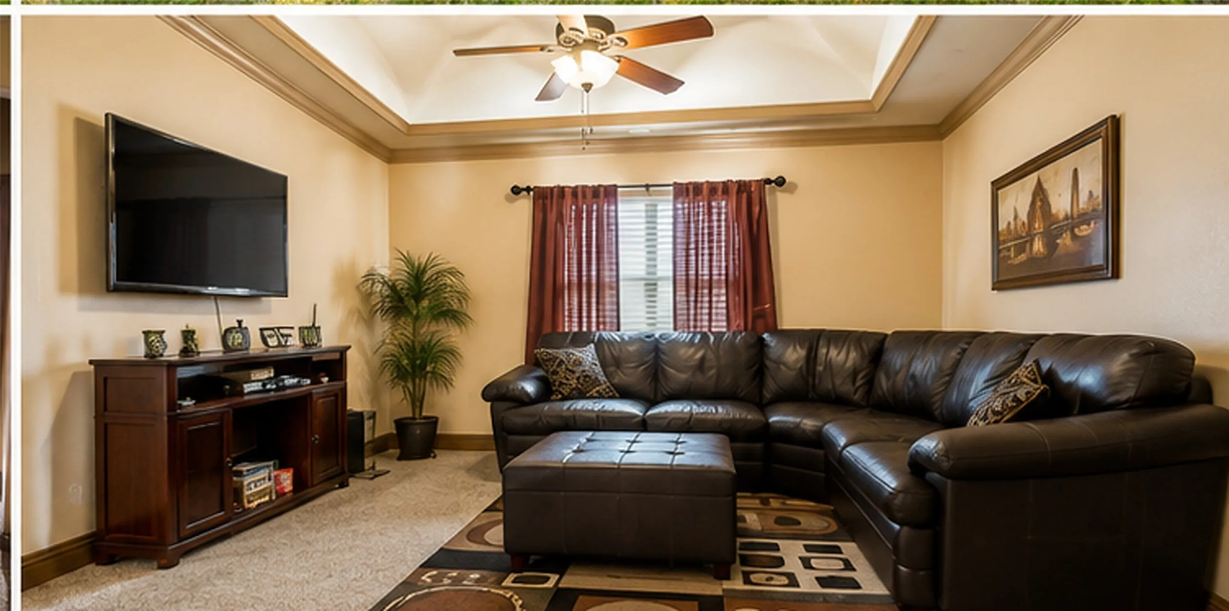 Tray ceiling with a ceiling fan, recessed window, and wall-mounted television