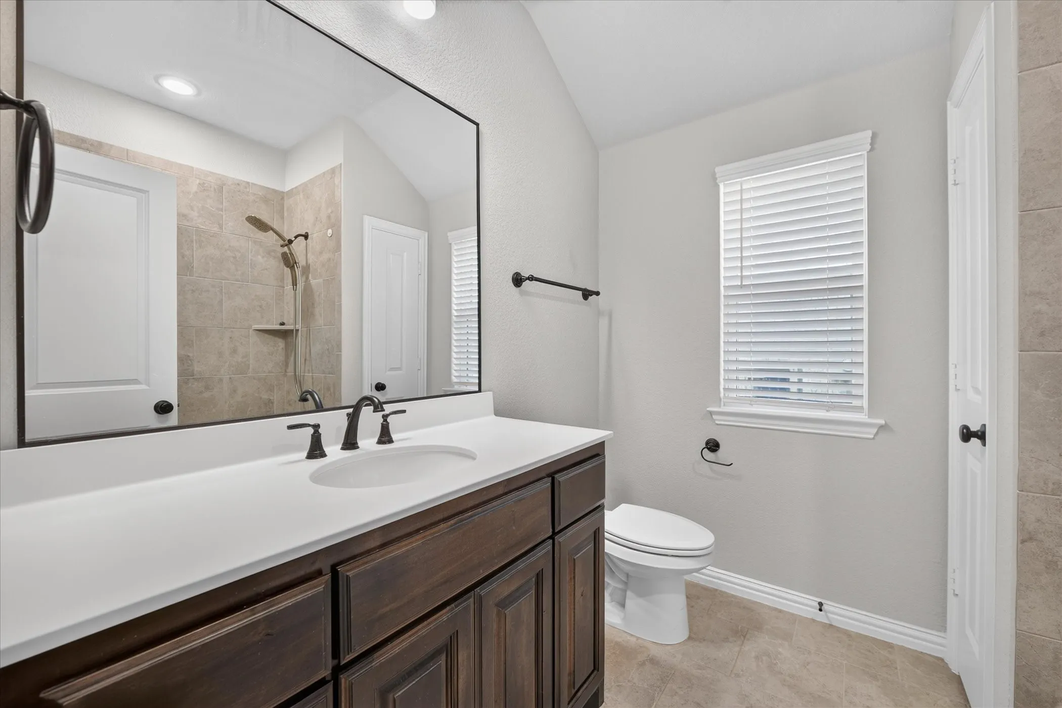 Vanity with white countertop, undermount sink, and dark wood-finish cabinetry