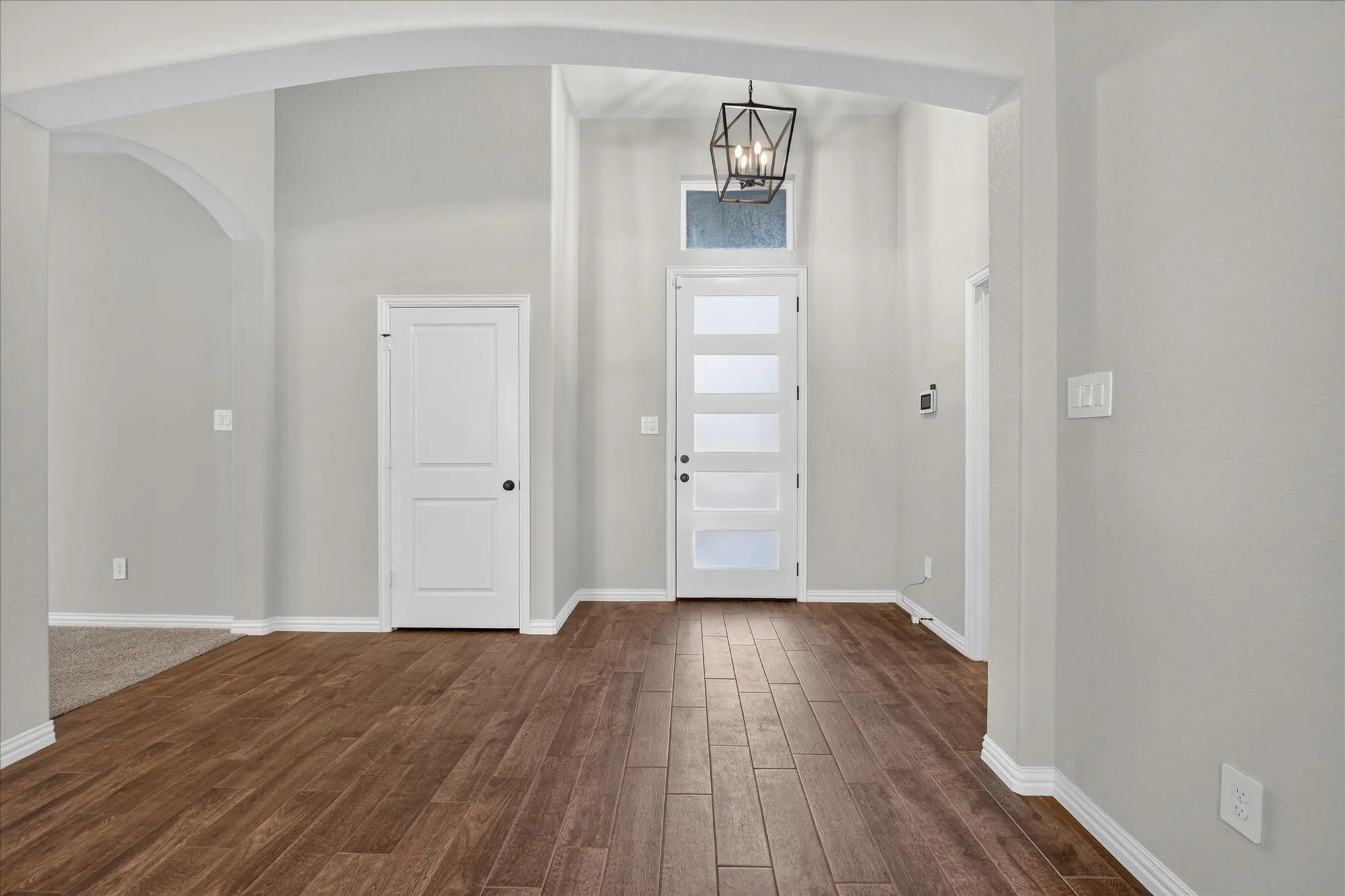 Entryway featuring wood-finish flooring, a modern front door with frosted glass panels, and a geometric pendant light fixture