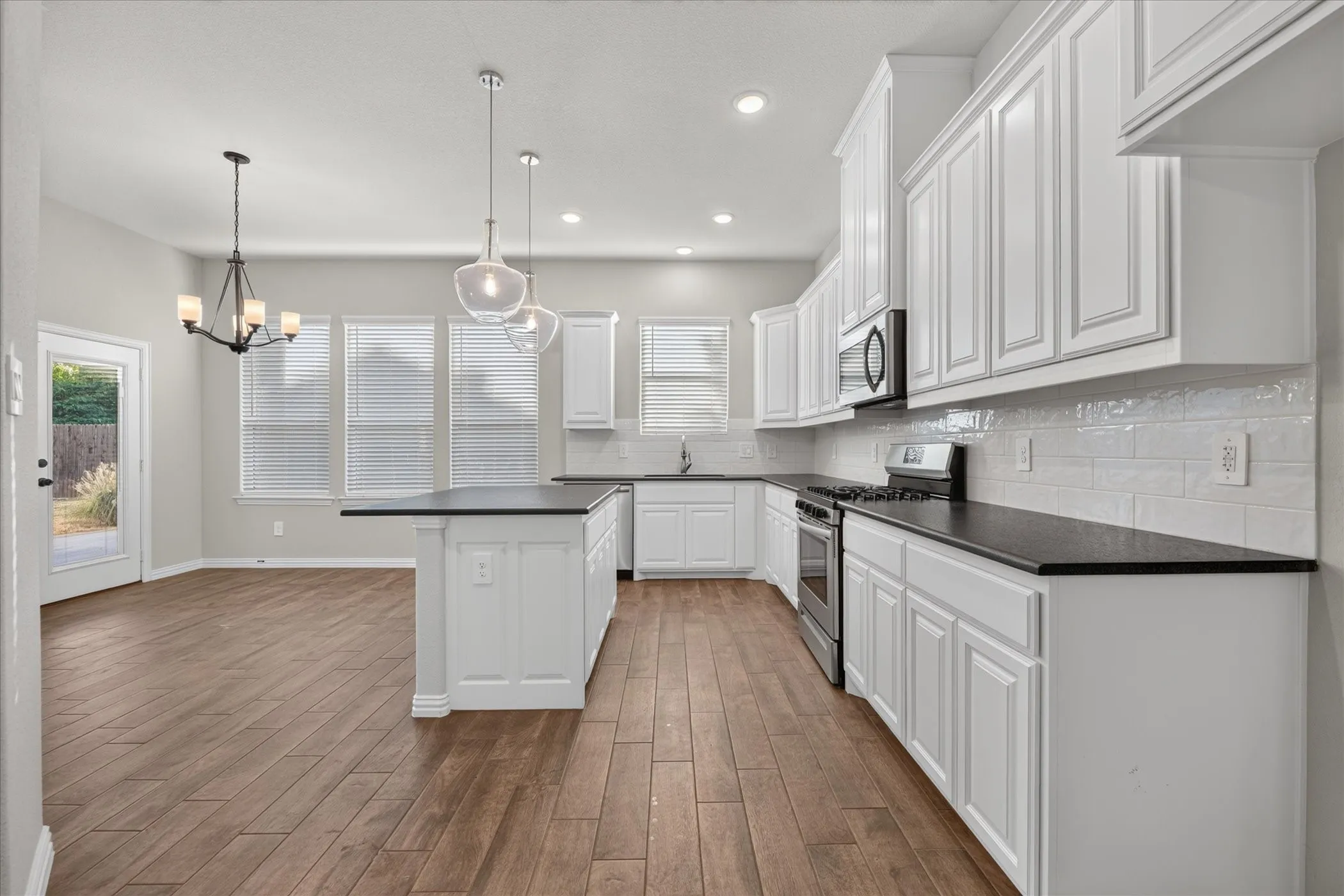 Modern kitchen featuring white cabinetry, dark countertops, a stainless steel range, and wood-finish flooring