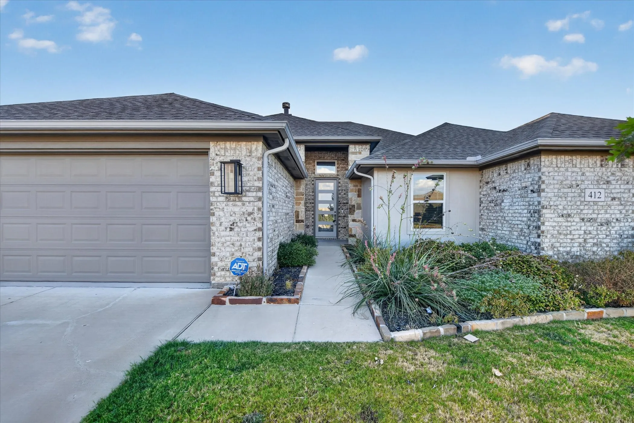 Modern exterior with a stone and stucco facade, a concrete driveway, a two-car garage, and a covered entry