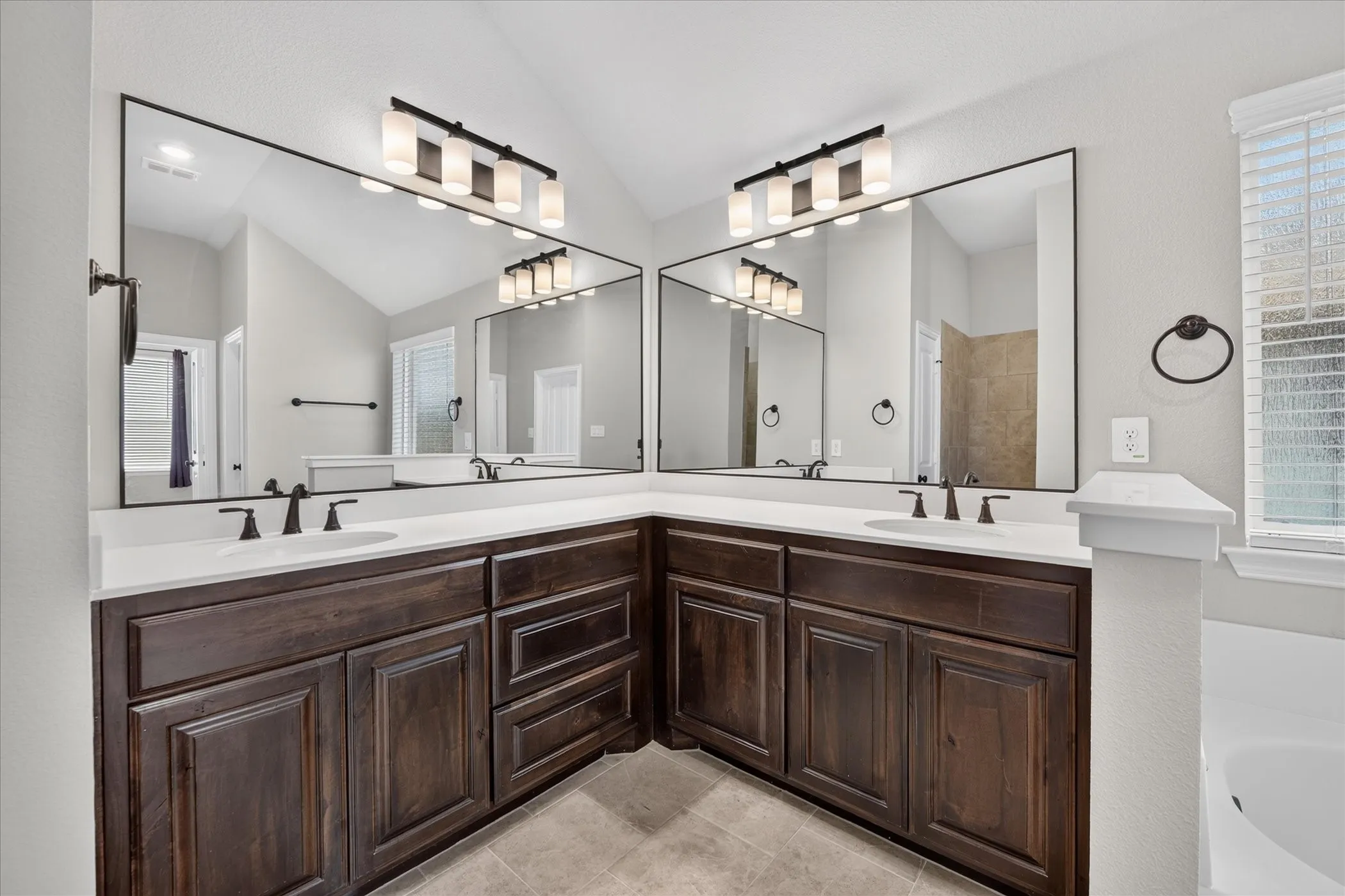 Dual vanity featuring dark wood-finish cabinetry, white countertops, and undermount sinks with matte black fixtures