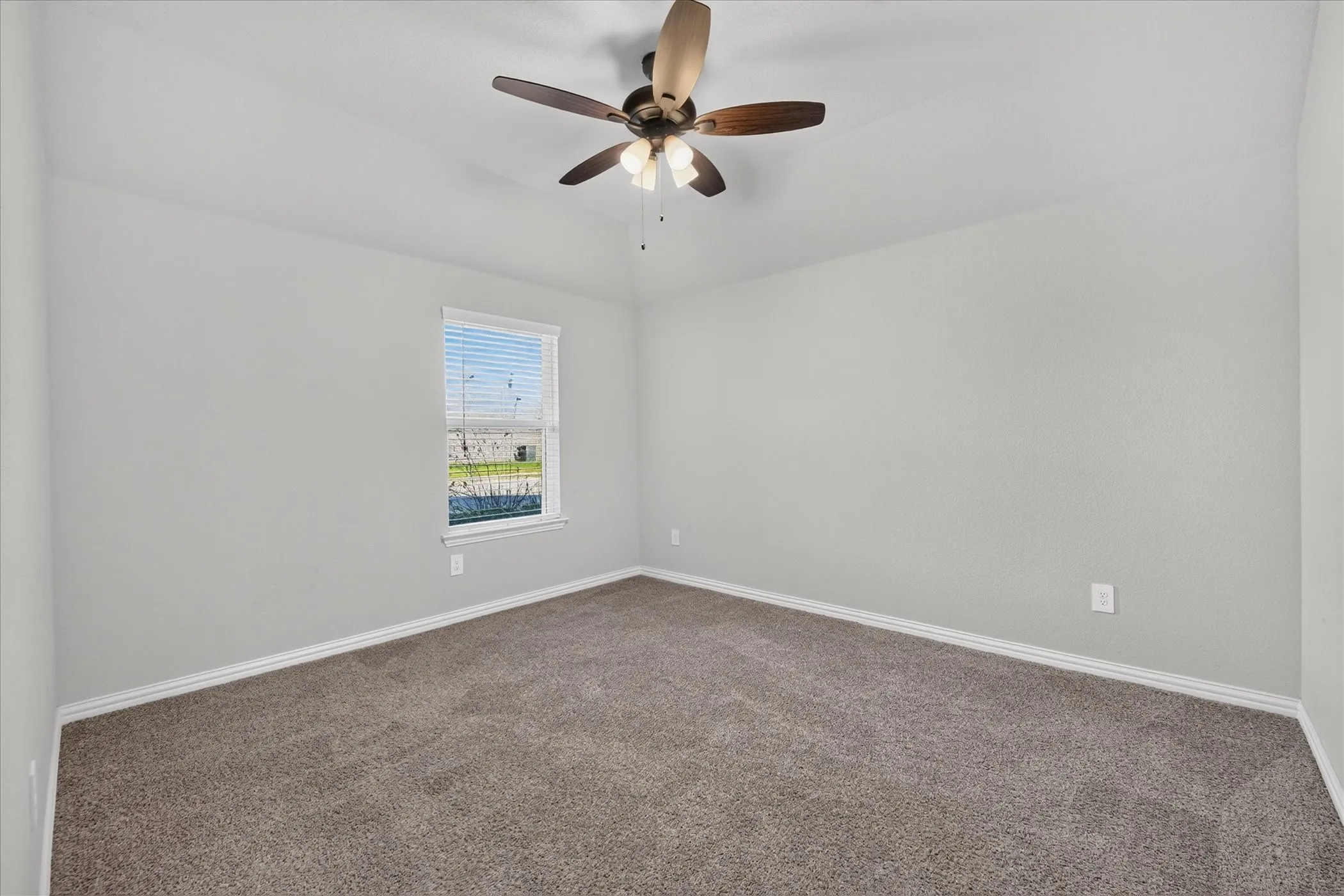Neutral gray walls and a vaulted ceiling with a ceiling fan