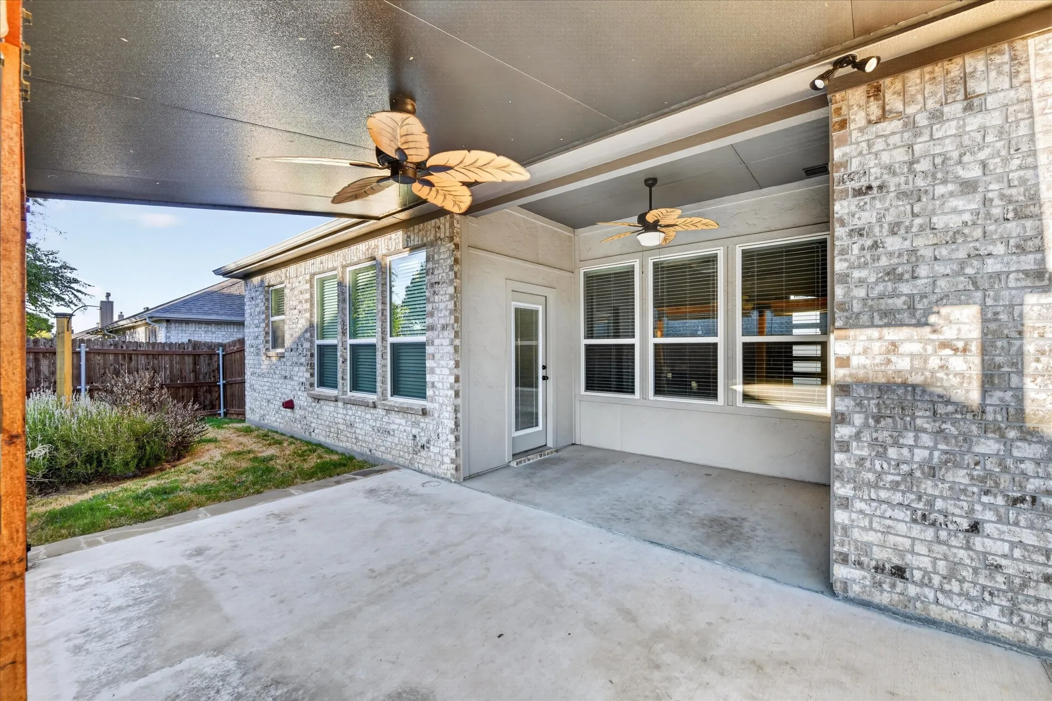 Covered patio with a concrete surface and two ceiling fans