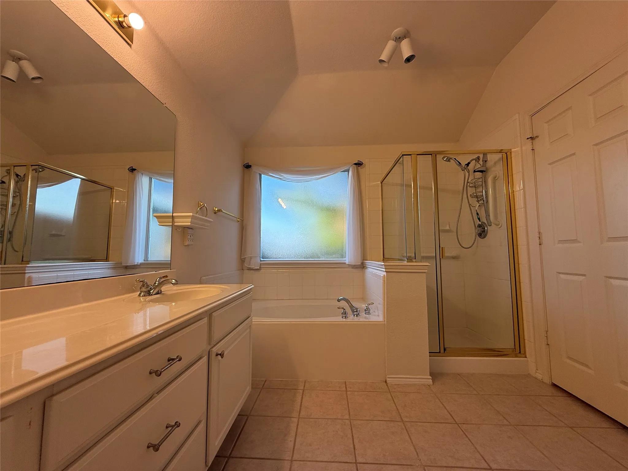 Bathroom featuring a vanity with integrated sink, a soaking tub, and a separate shower with a glass enclosure