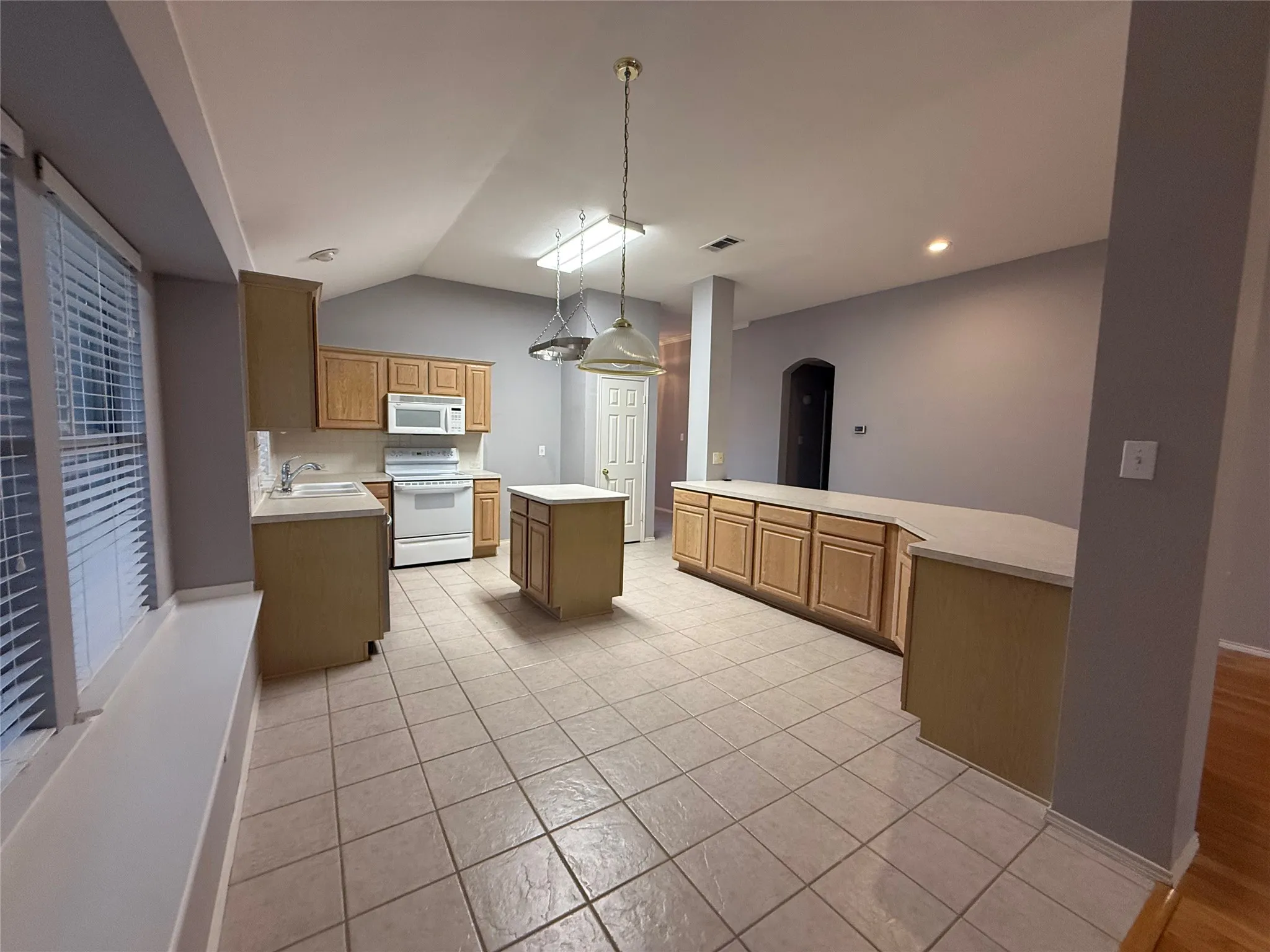 Kitchen featuring a vaulted ceiling, recessed lighting, a skylight, an eat-at counter, and tile flooring