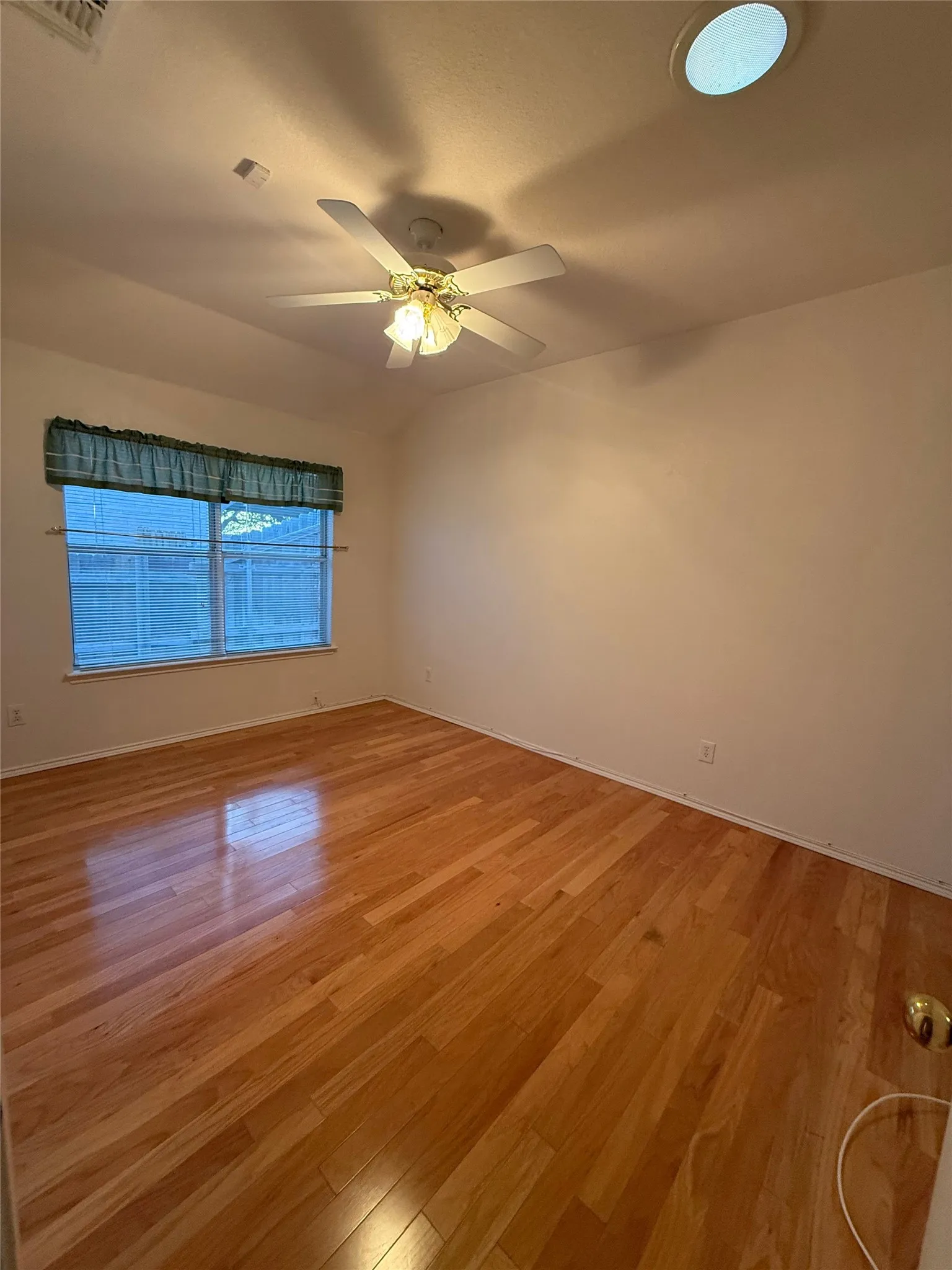 Wood-finish flooring, ceiling fan with integrated lighting, recessed ceiling light, and window with privacy fencing