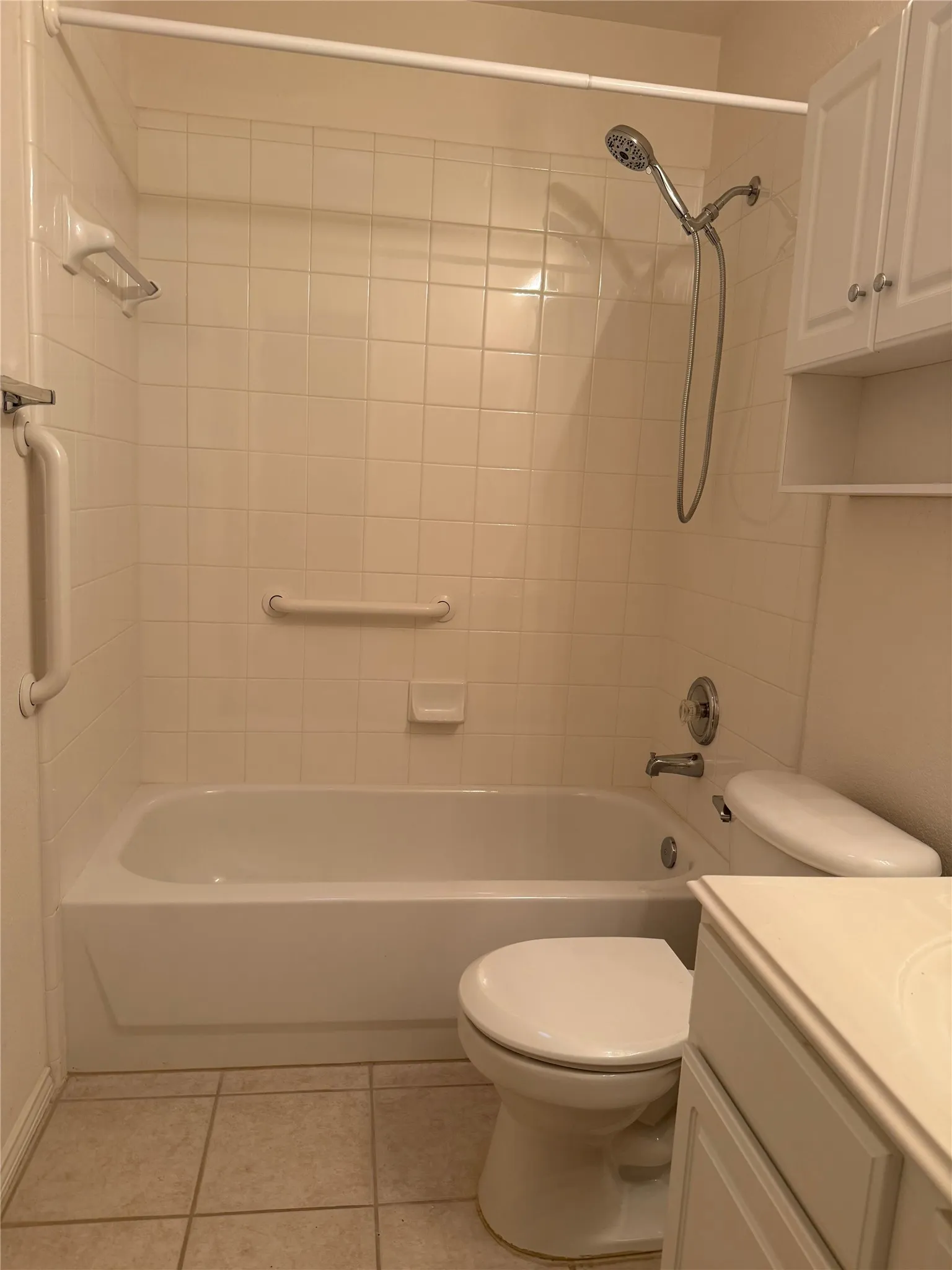 Bathroom featuring a tub/shower combination with tile surround, a wall-mounted showerhead, and a vanity with white cabinetry