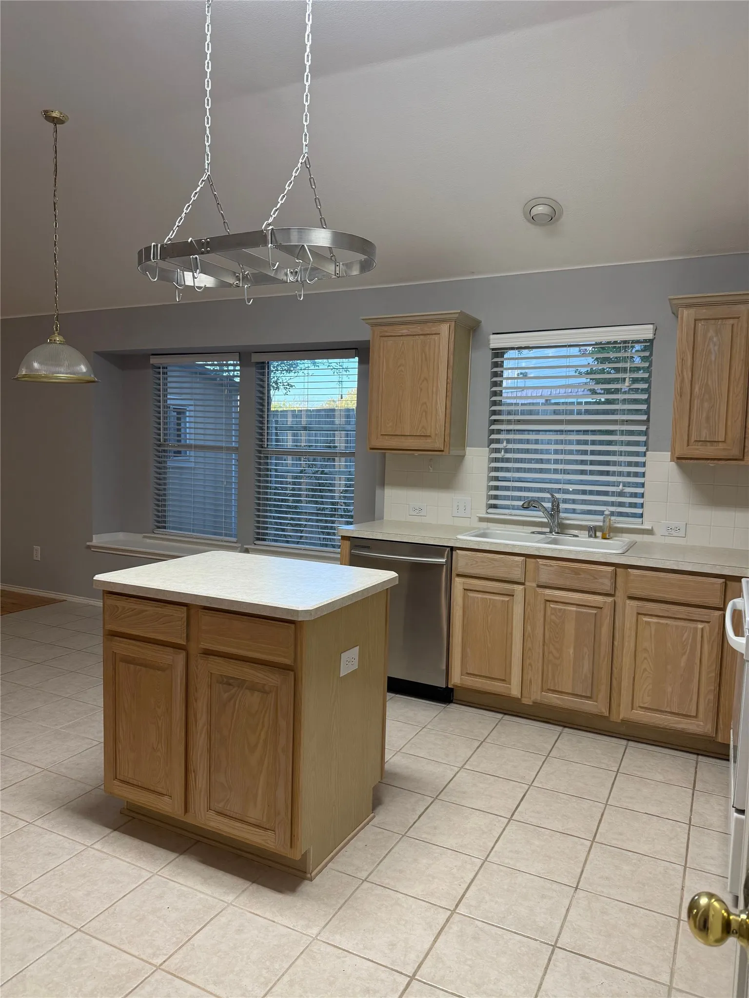 Kitchen featuring light wood-finish cabinetry, tile flooring, and a center island with a light-toned countertop