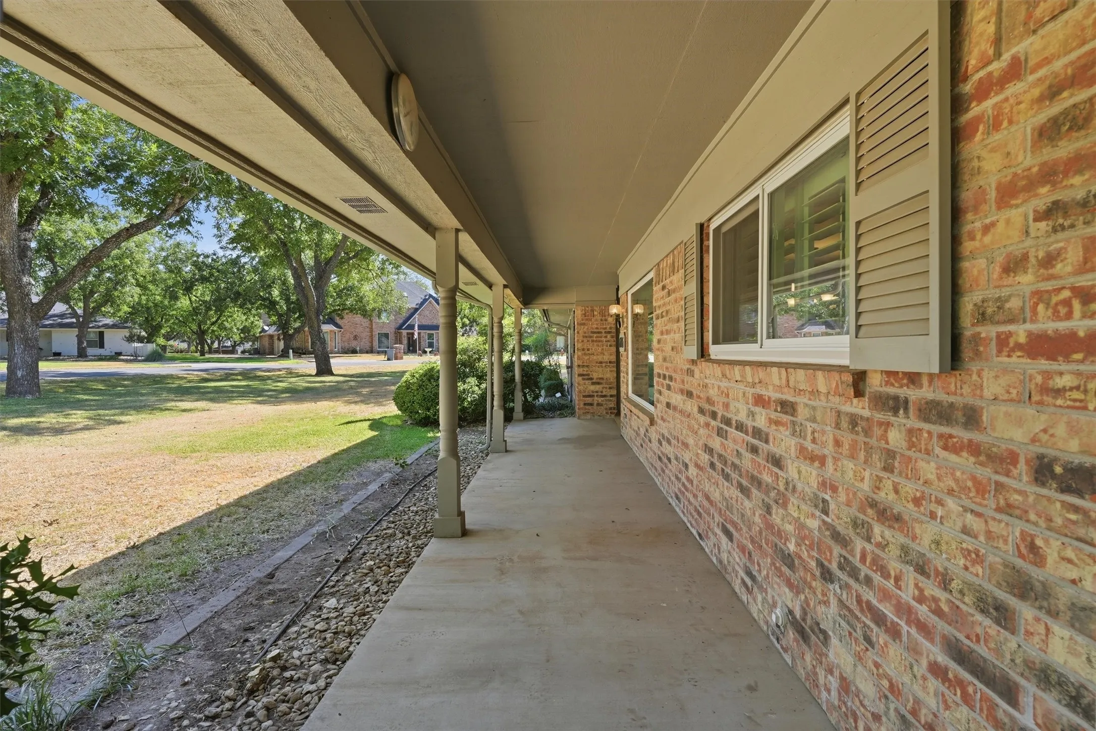 Brick exterior with a covered porch, white-framed windows, and decorative shutters