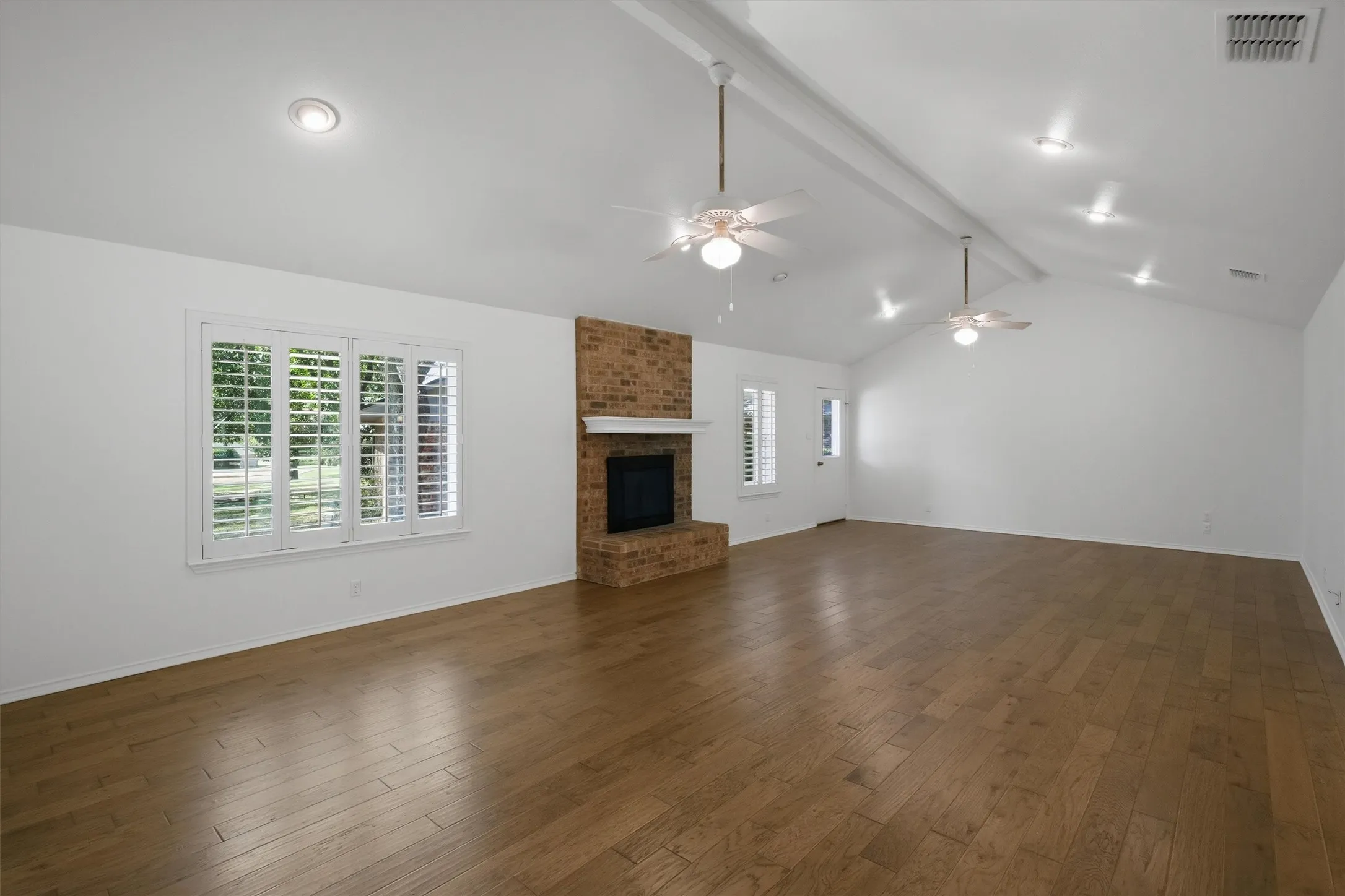 Vaulted ceiling with exposed beam, recessed lighting, and two ceiling fans