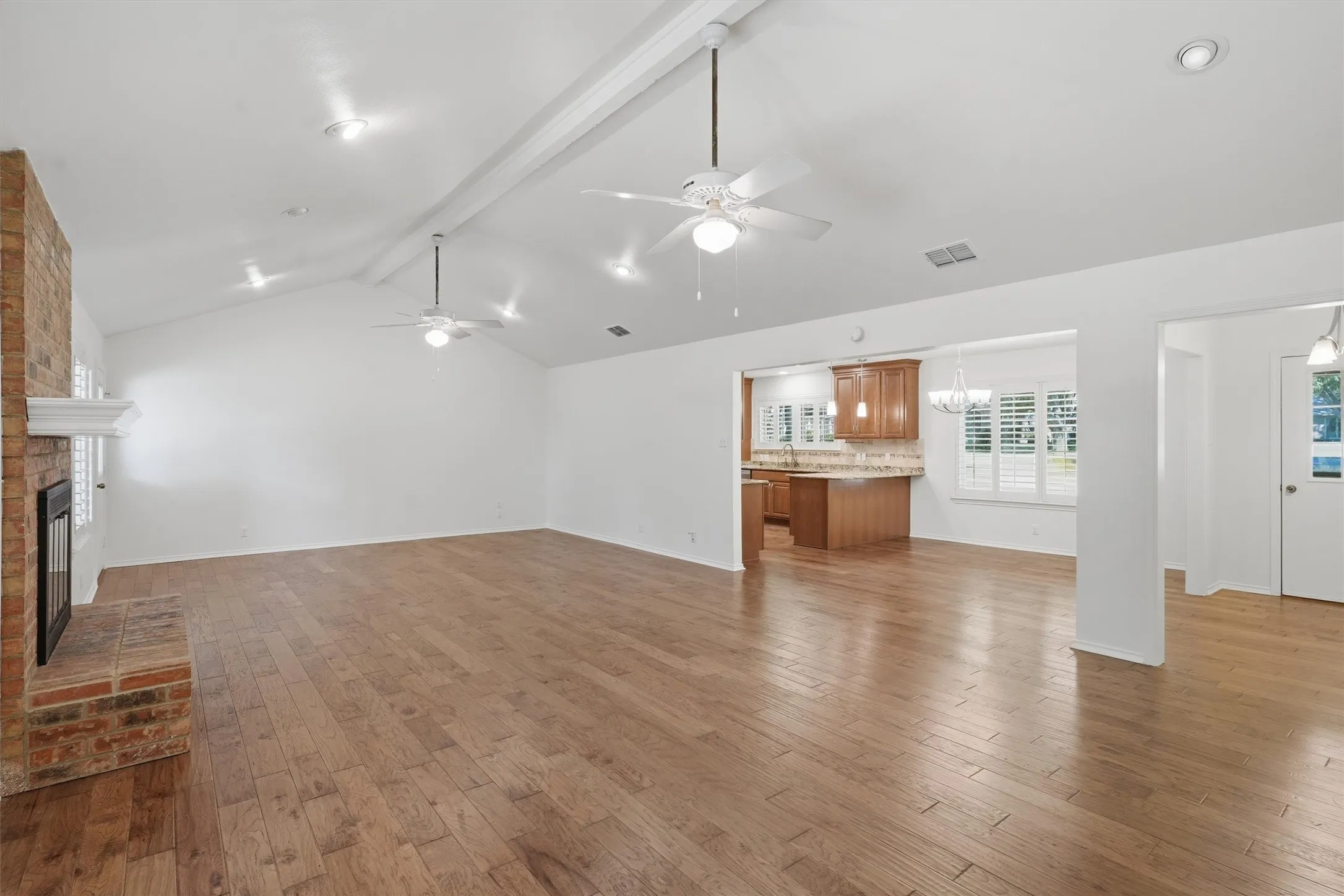 Vaulted ceiling with recessed lighting, wood-finish flooring, brick fireplace with mantel, and ceiling fans