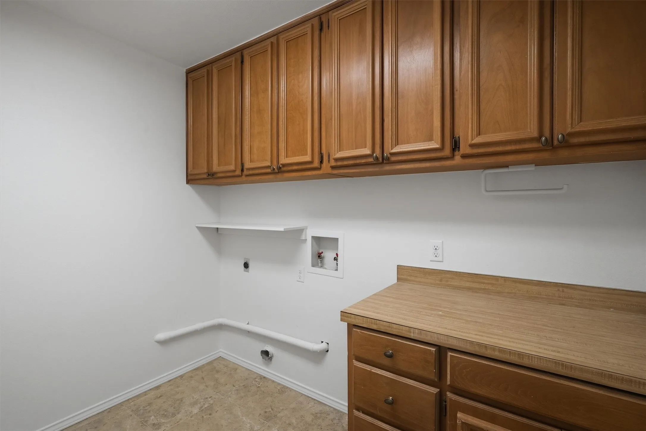Wood-finish cabinetry with brass hardware, wood-finish countertop, and functional upper shelving