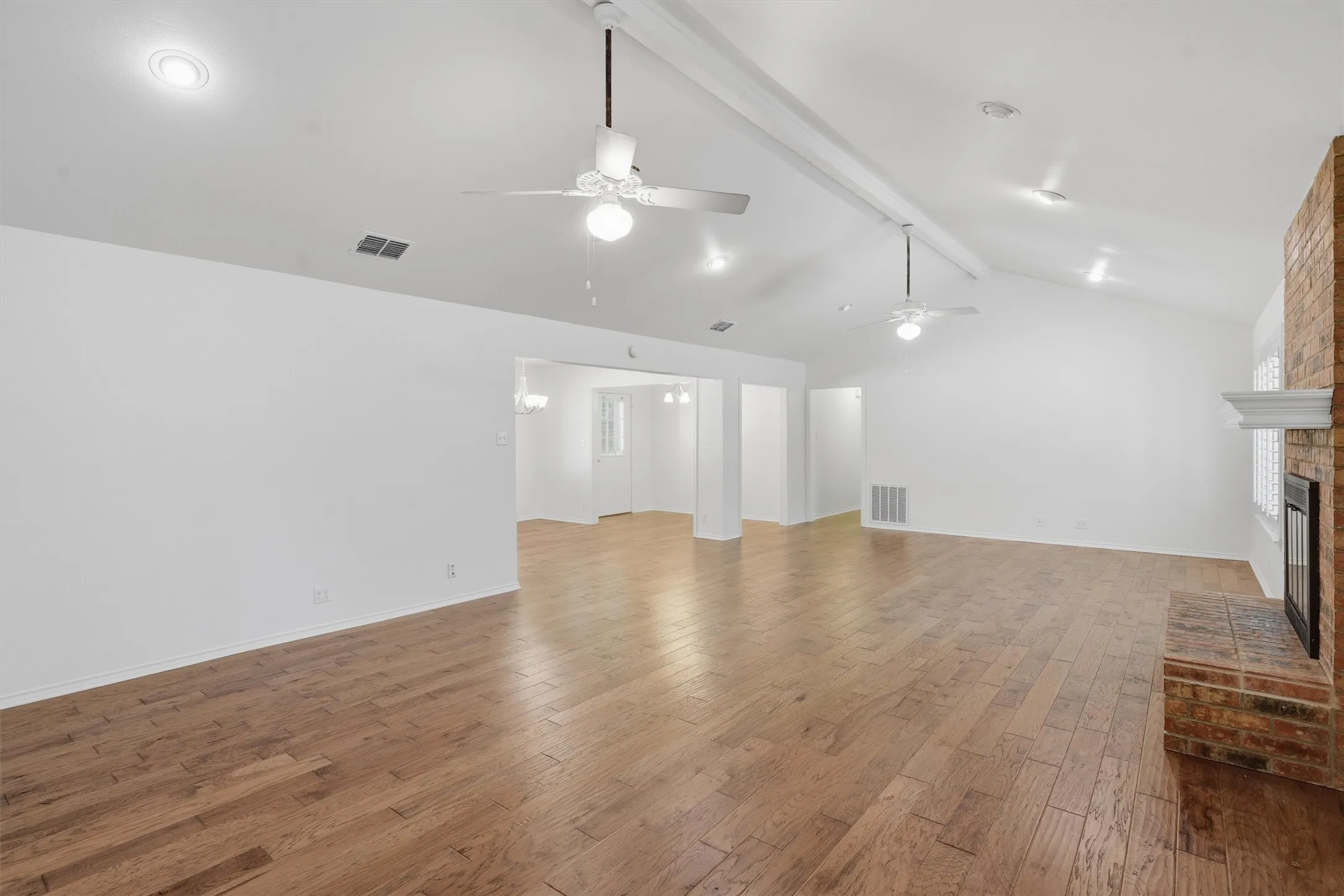 Vaulted ceilings with recessed lighting, wood-finish flooring, brick fireplace with mantel, and ceiling fans