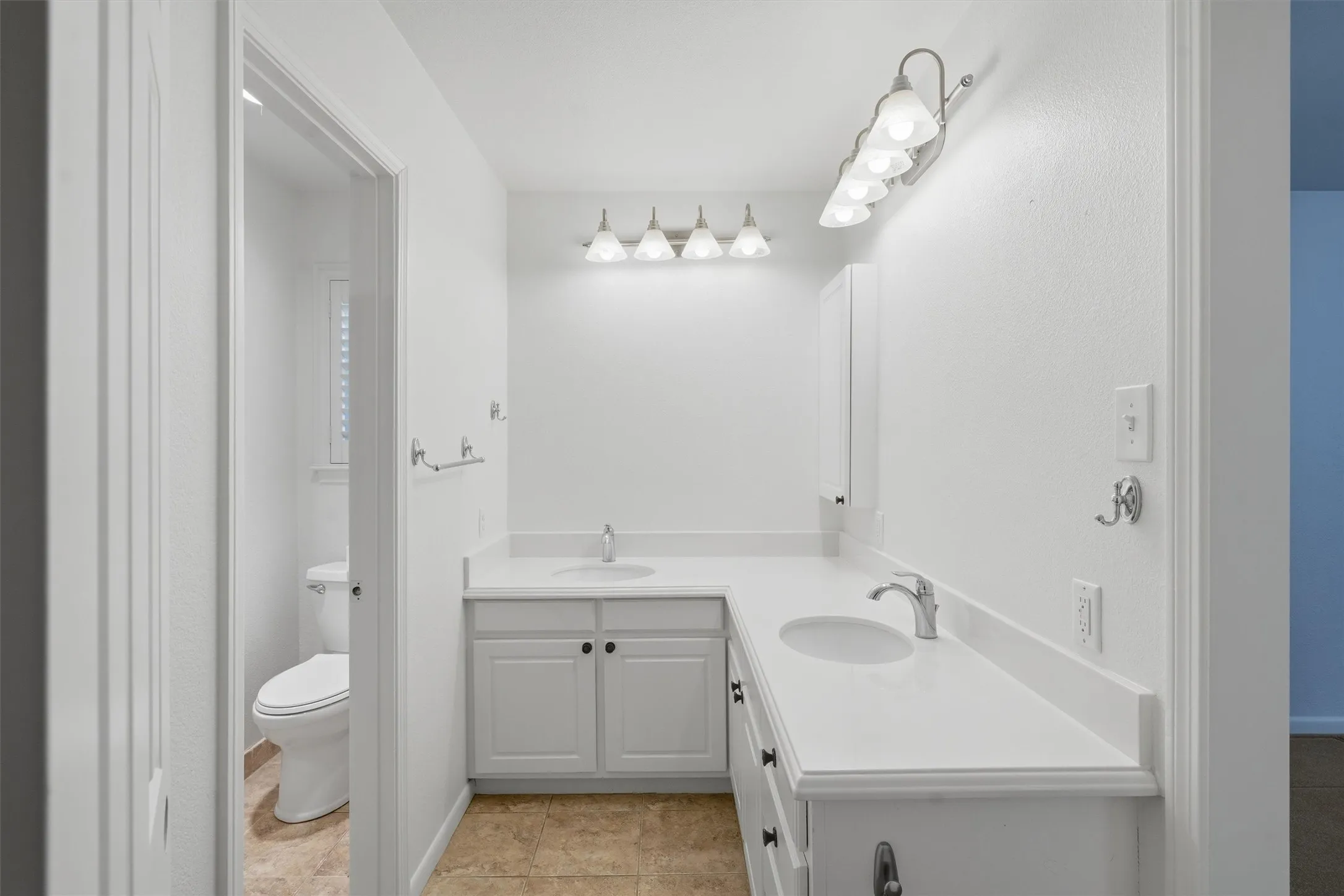 Dual vanity with white cabinetry and integrated sinks, chrome fixtures, and overhead lighting