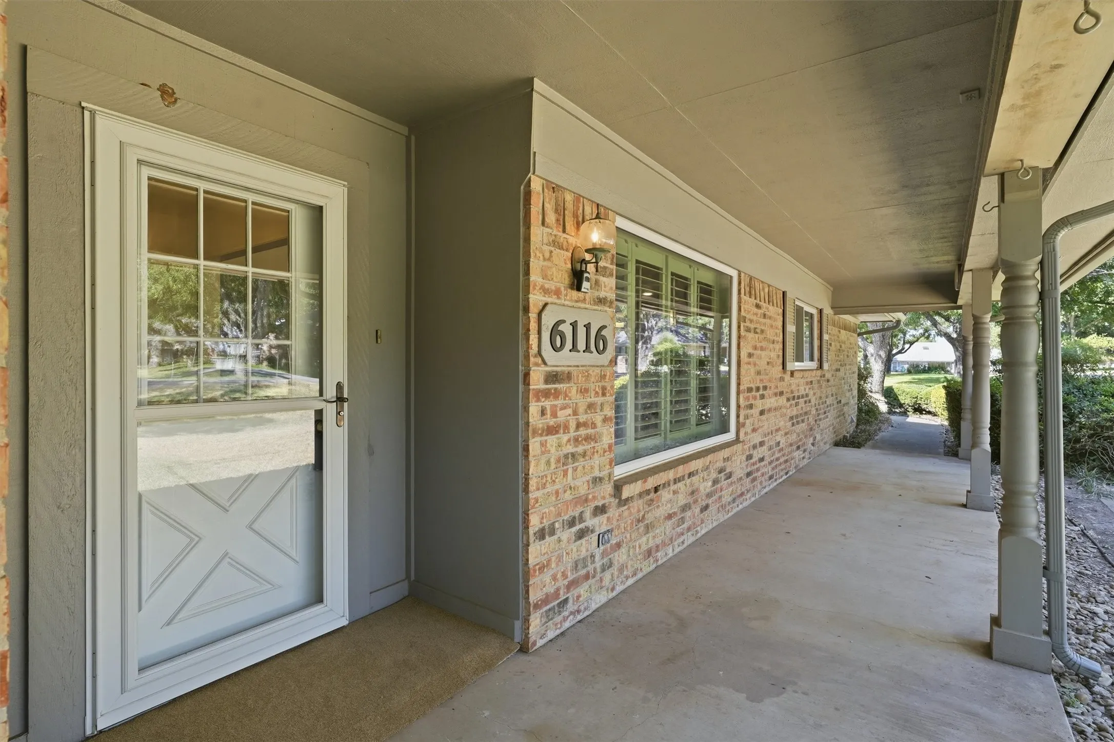 Brick exterior with a covered porch, decorative porch columns, and a storm door entry