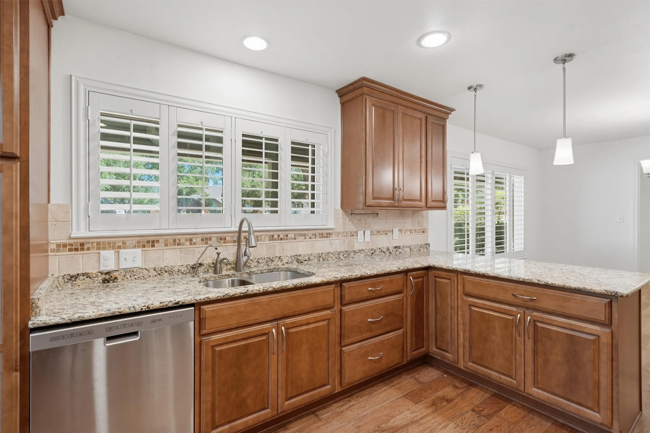 Kitchen featuring wood-finish cabinetry, stone countertops, stainless steel appliances, and a mosaic tile backsplash