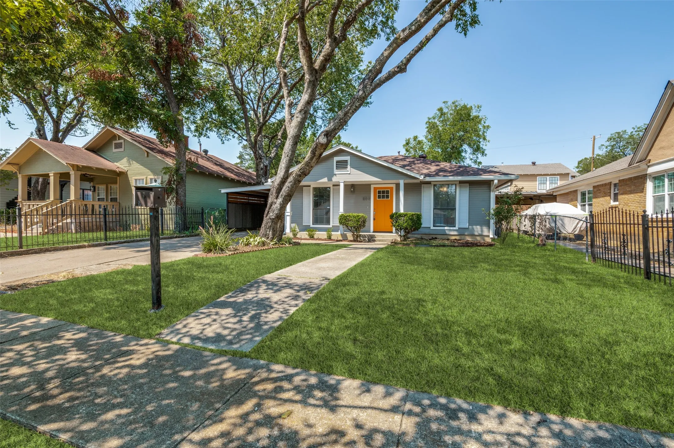 Single-story residence with a covered front entry, vibrant orange front door, and a concrete walkway