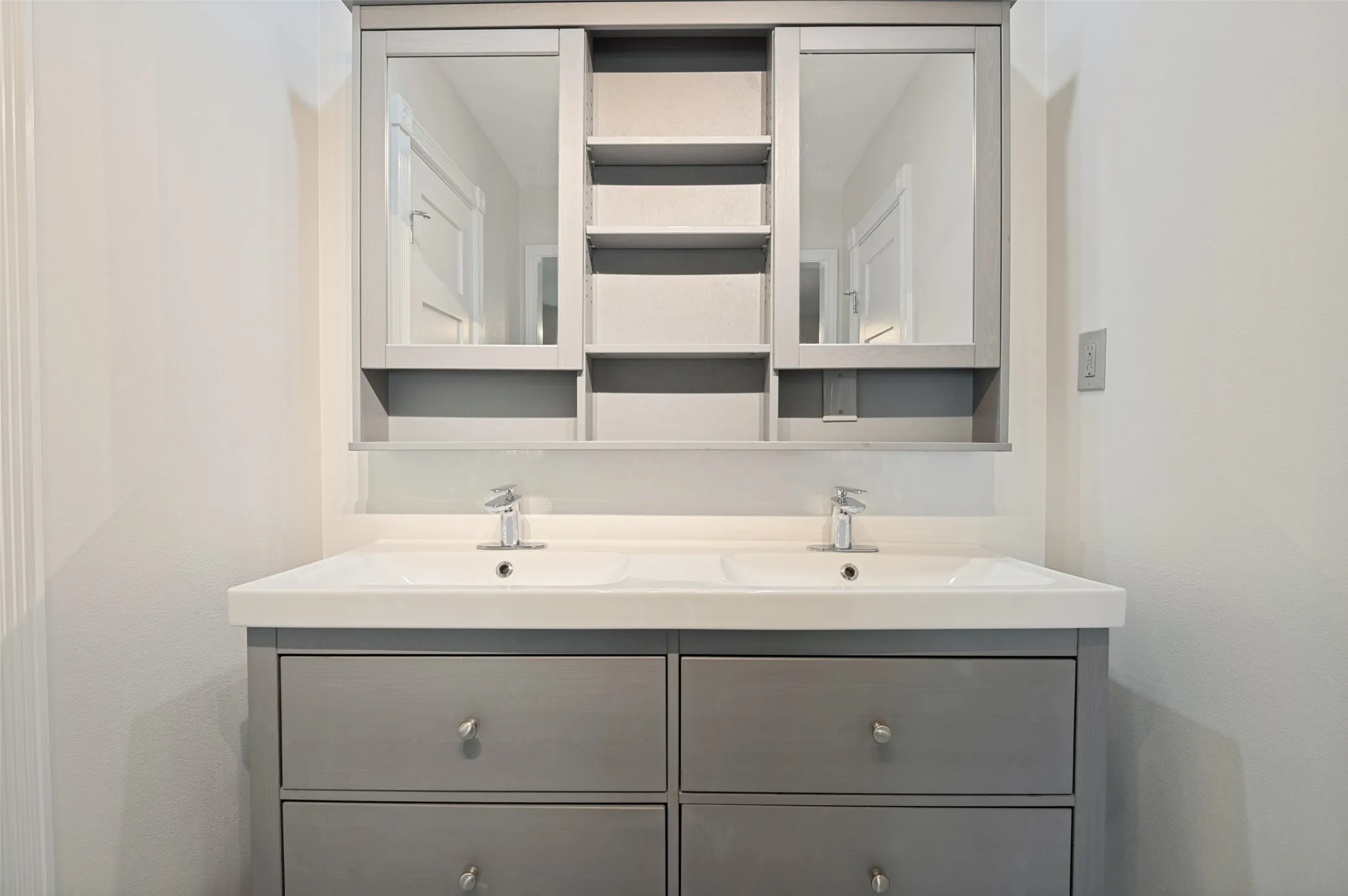 Dual integrated sinks with chrome faucets, set in a gray vanity with four drawers