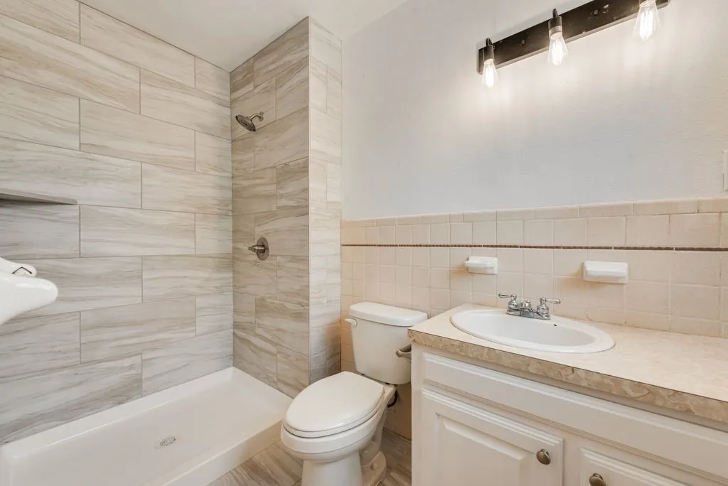 Walk-in shower with large format tile, built-in shower niche, chrome fixtures, single vanity with integrated sink, and track lighting