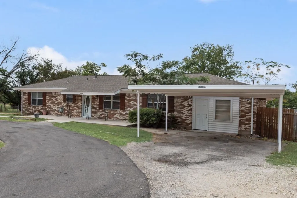 Brick exterior with dark shutters, covered carport, and a paved driveway