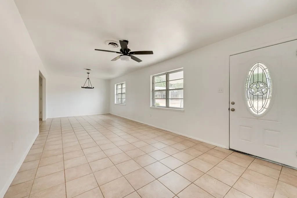 Tiled flooring with a neutral finish, white walls, and a ceiling fan with integrated lighting