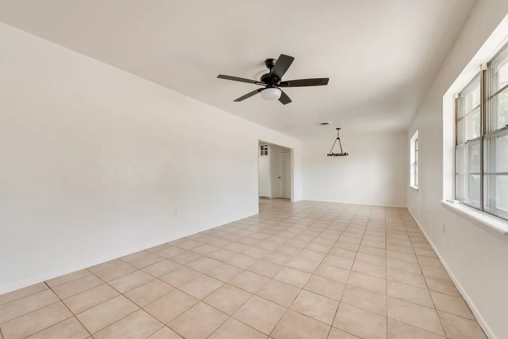 Spacious room with light-toned tiled flooring, large windows, and a ceiling fan with integrated lighting