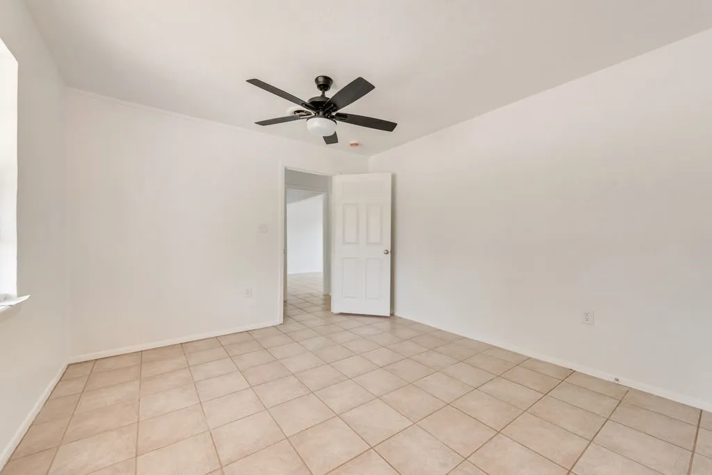 Light-colored tile flooring, white walls, and a ceiling-mounted fan with integrated lighting