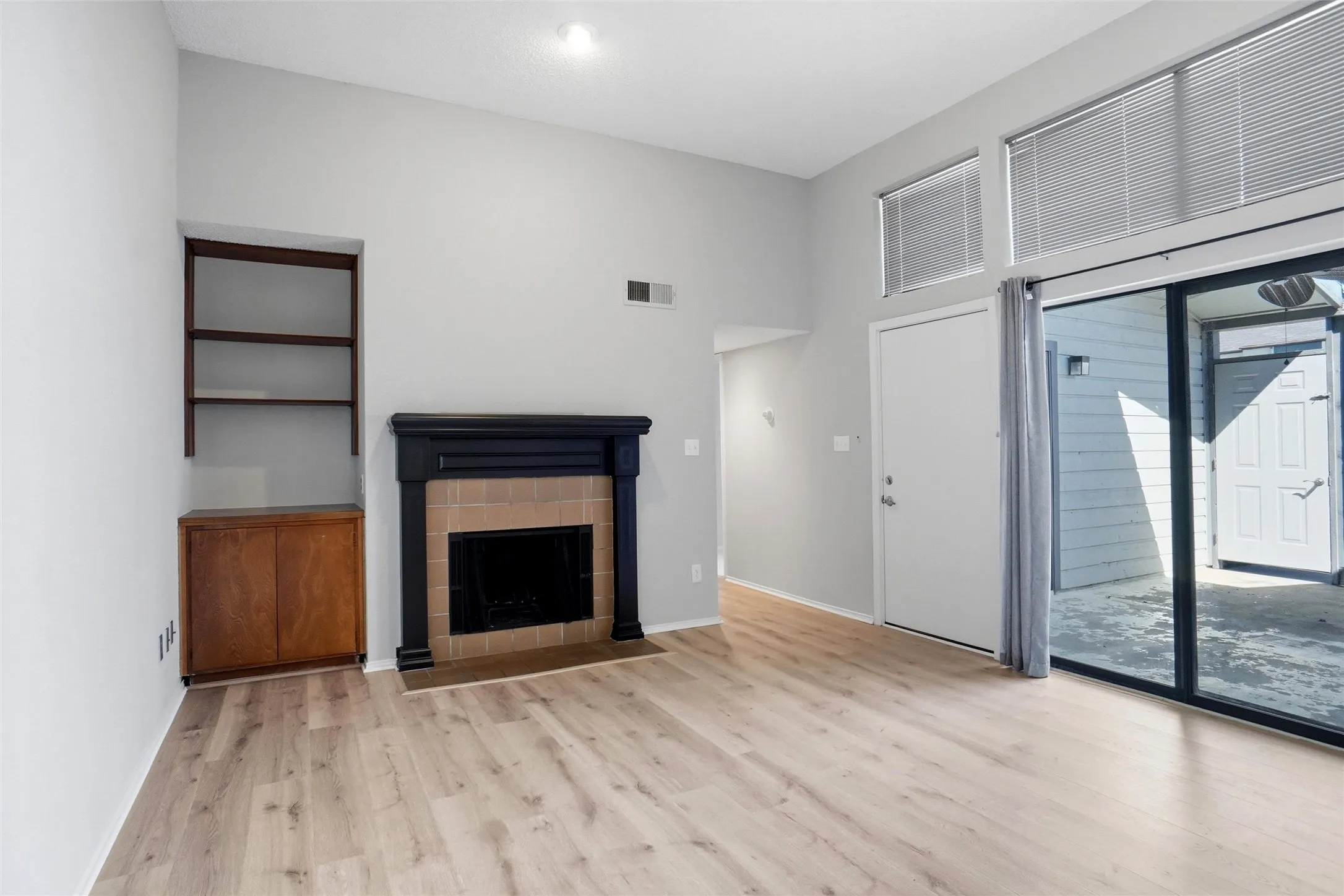 Living area featuring Luxury Vinyl Plank flooring, wood burning fireplace, black pedestal mantle, tile surround, Built-in shelving & cabinetry for Media Center