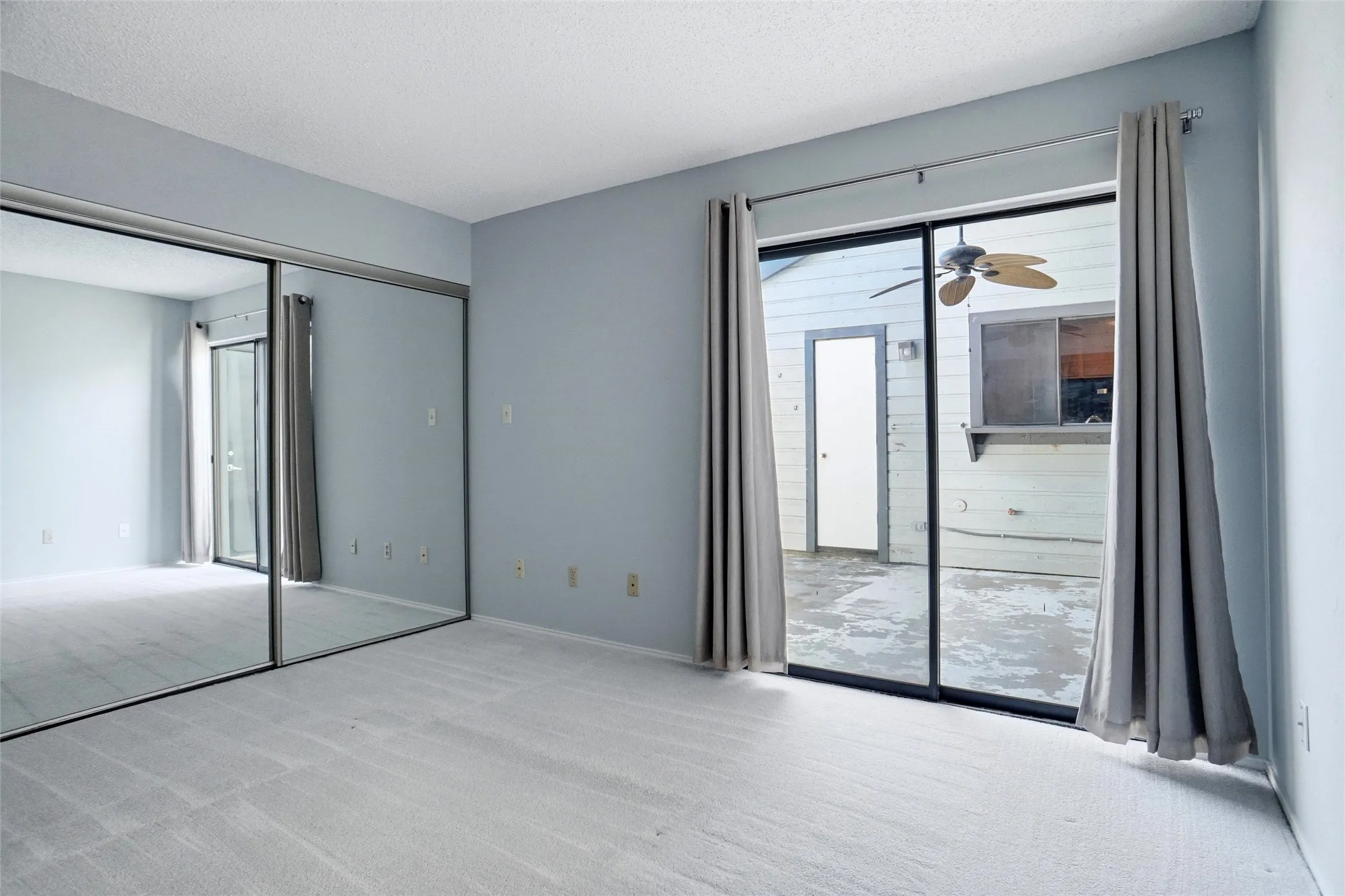 Full Wall Sliding mirror closet doors, light-toned carpet, and sliding glass door leads to outdoor space