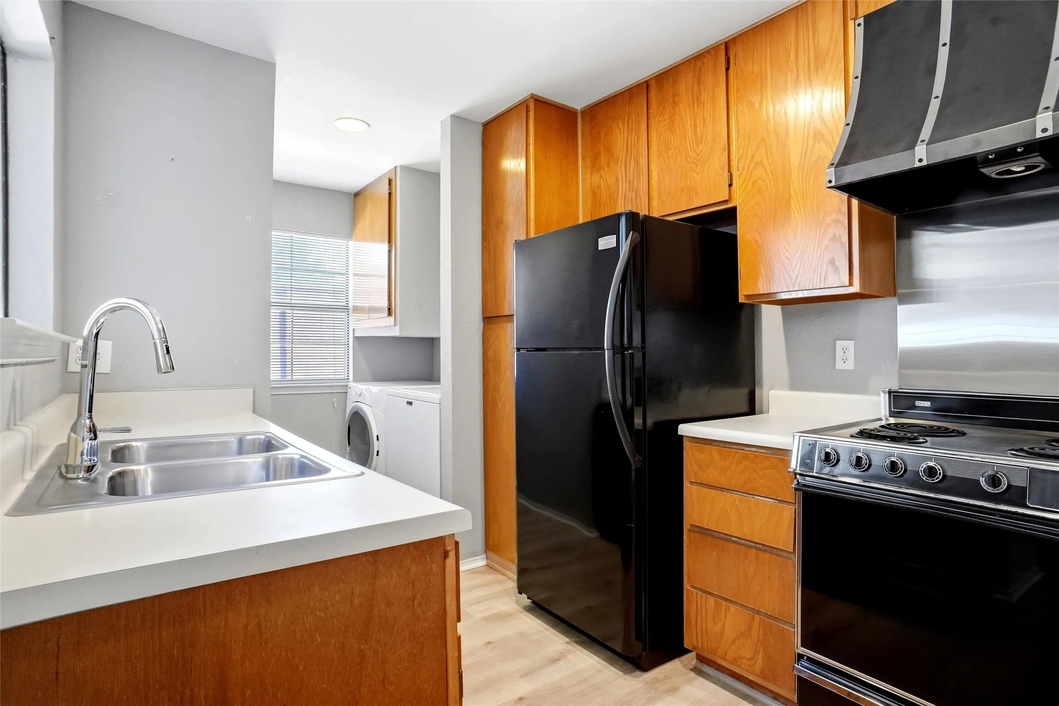 Galley Kitchen has white countertops, stainless steel sink, and wood-finish cabinetry