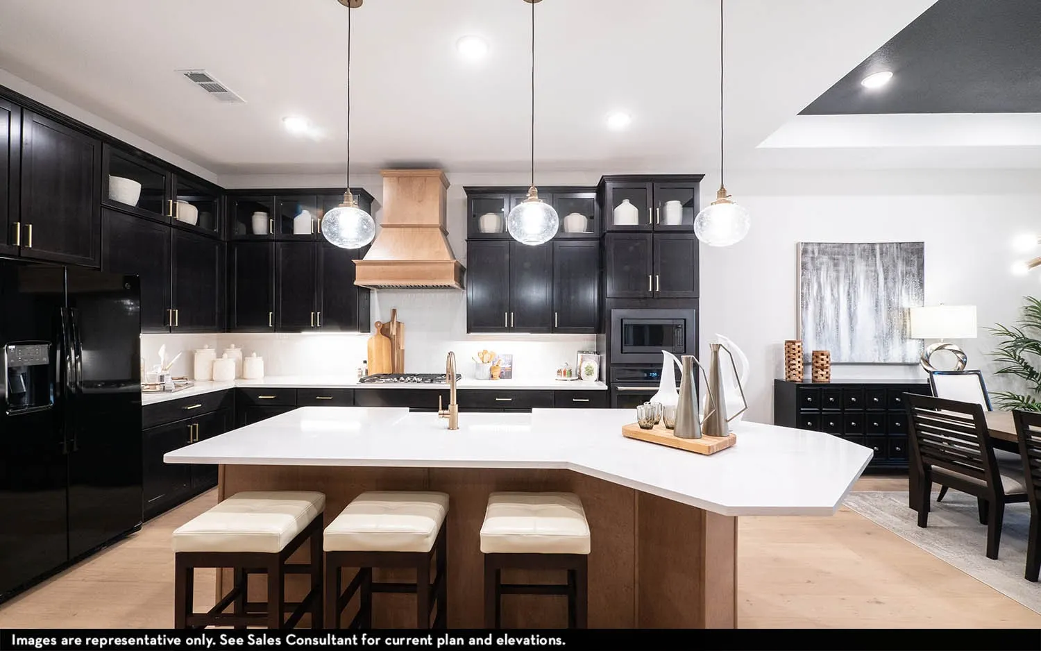 Gourmet kitchen with dark cabinetry, integrated appliances, wood-finish flooring, a central island with countertop seating, and decorative pendant lighting