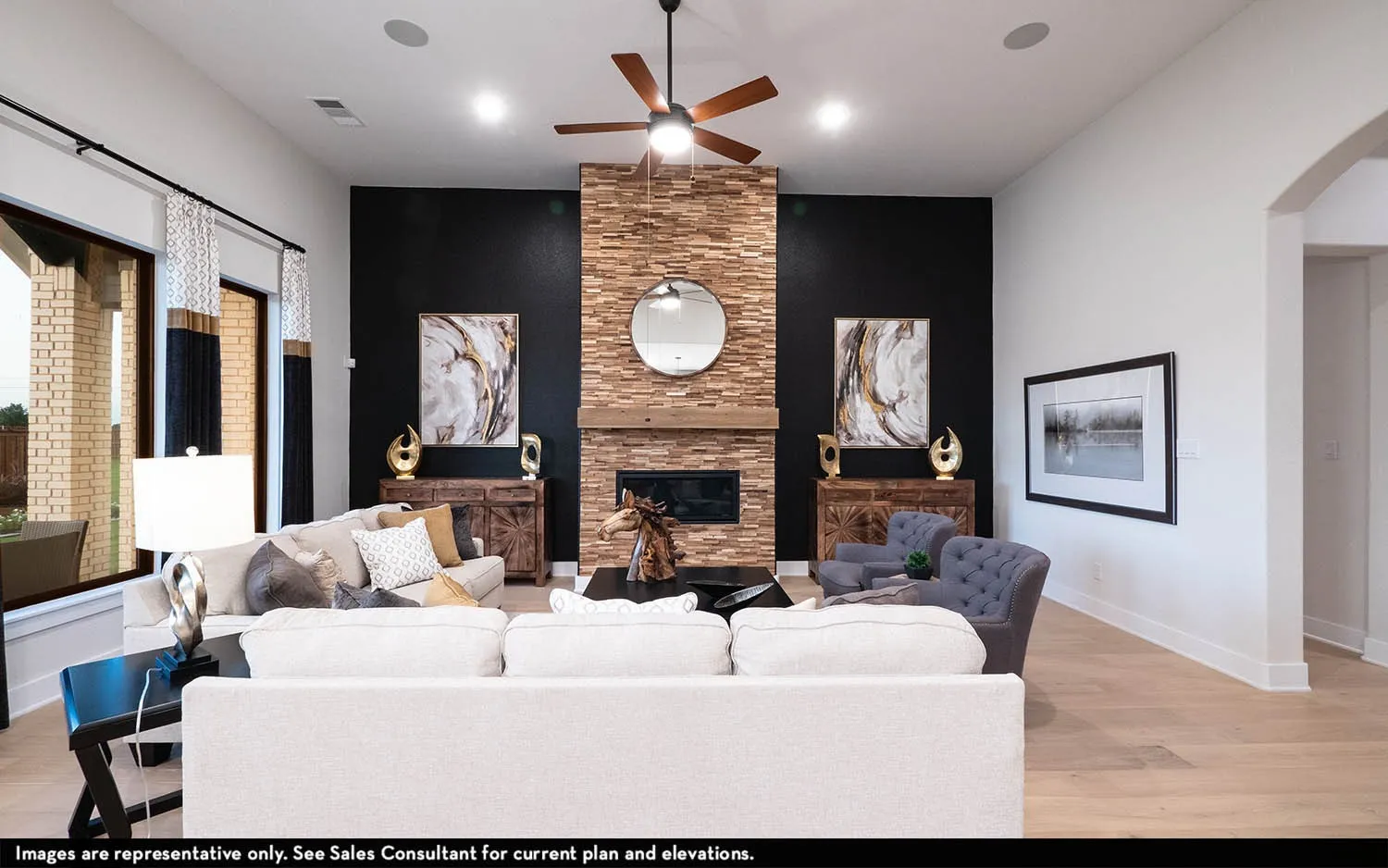 Spacious living area featuring a stone-clad fireplace with a wood mantel, high ceilings, wood-finish flooring, and large windows