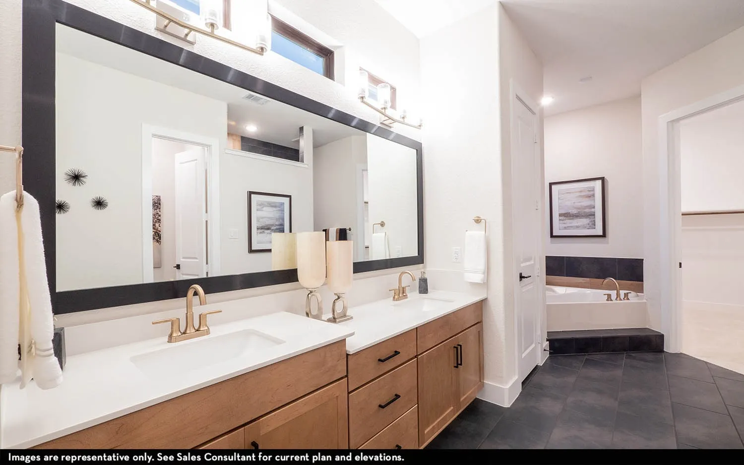 Double vanity with light wood-finish cabinetry, rectangular undermount sinks, and gold-finish fixtures