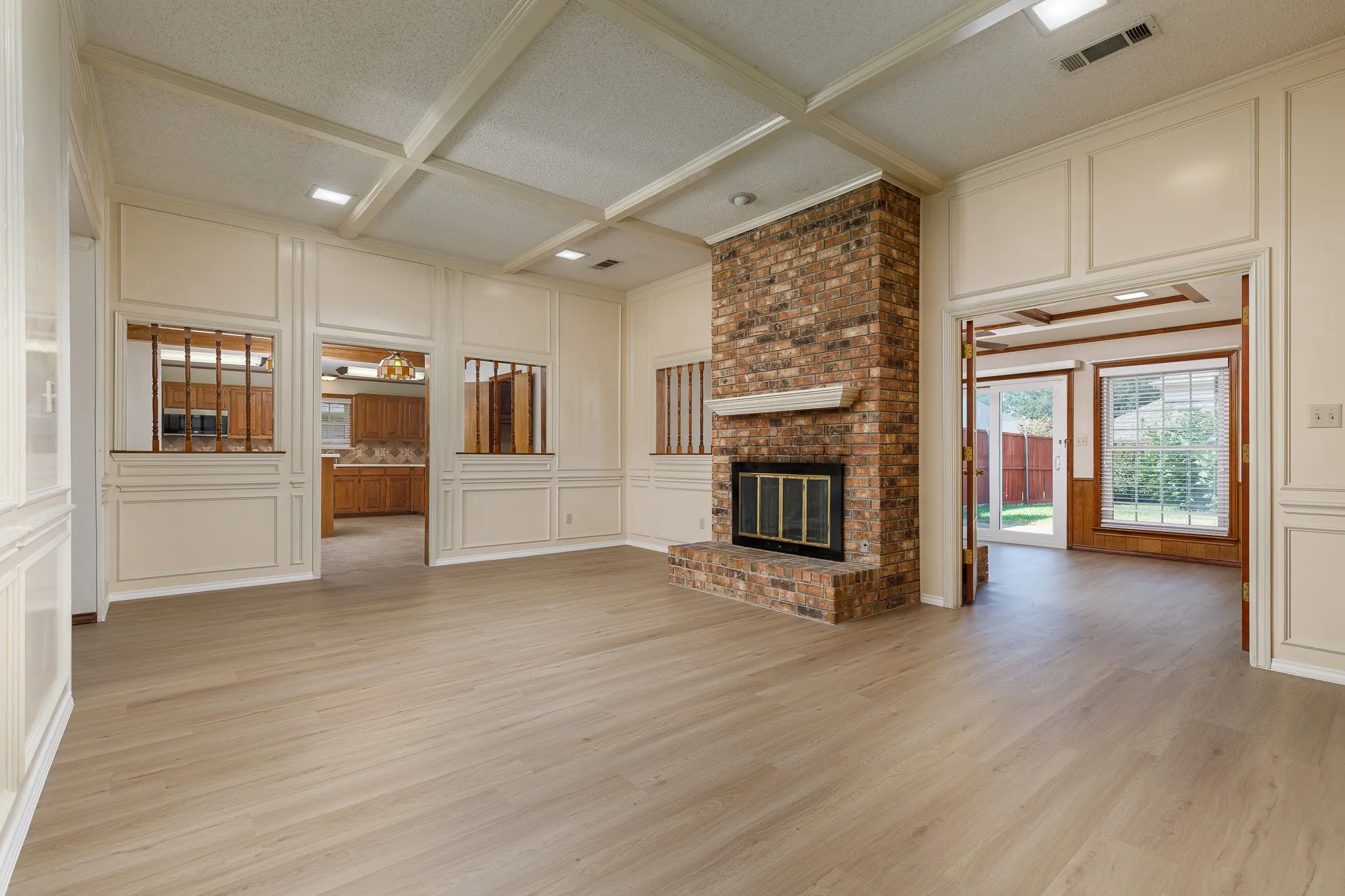Brick fireplace with a white mantel, wood-finish flooring, and paneled walls