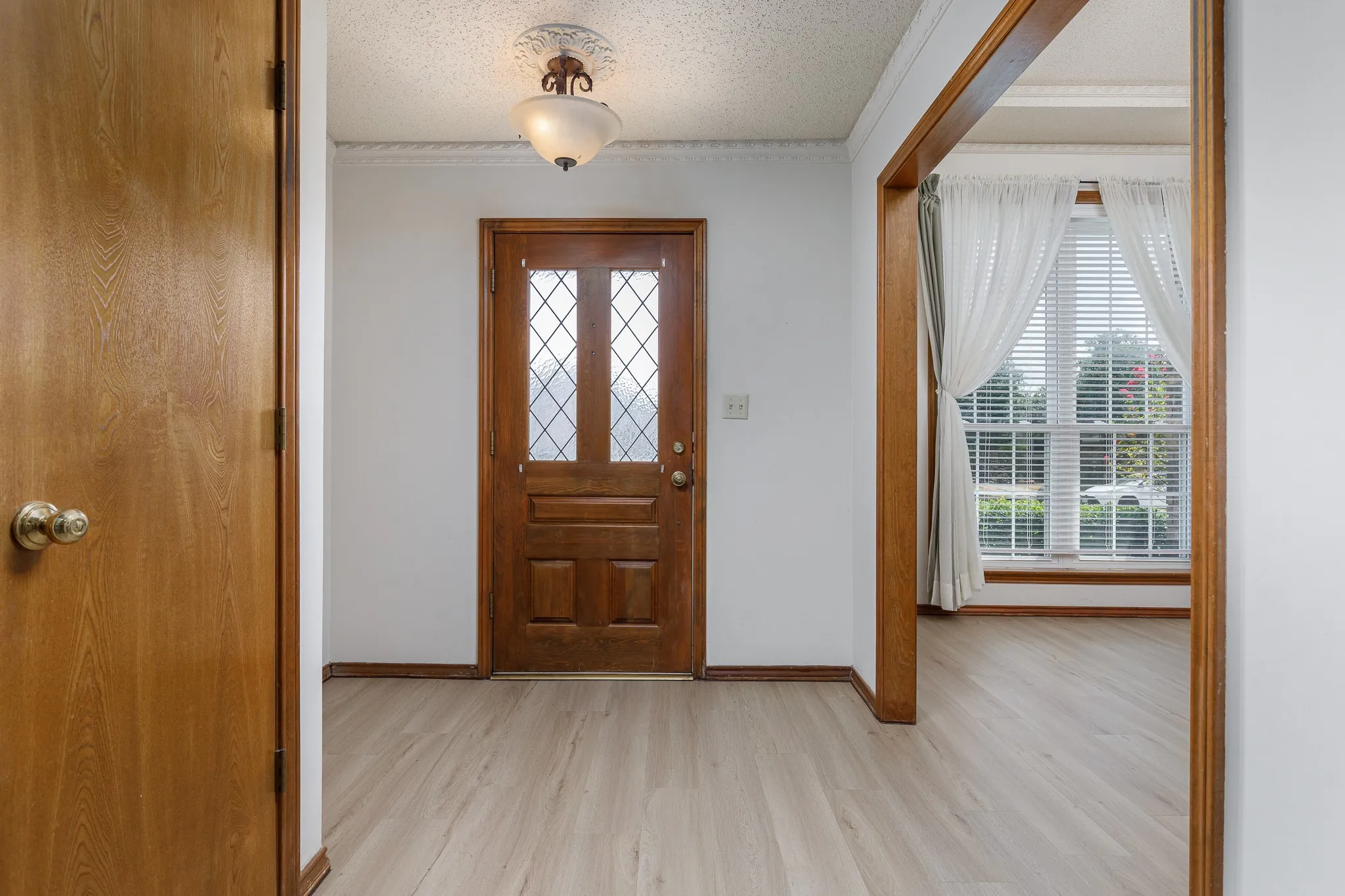 Entryway featuring wood-finish flooring, decorative ceiling fixture, and a solid wood entry door with leaded glass