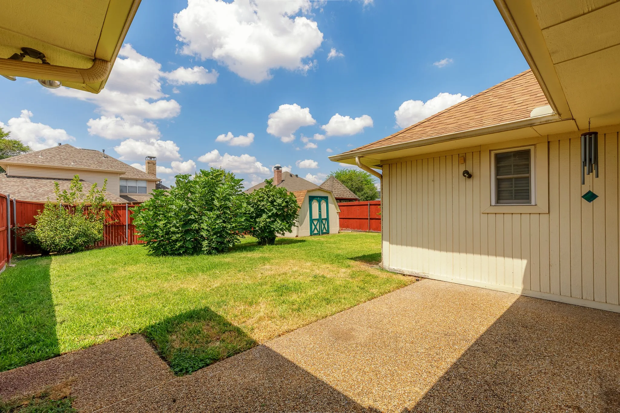 Expansive backyard featuring a manicured lawn, established shrubbery, a storage shed, and a privacy fence