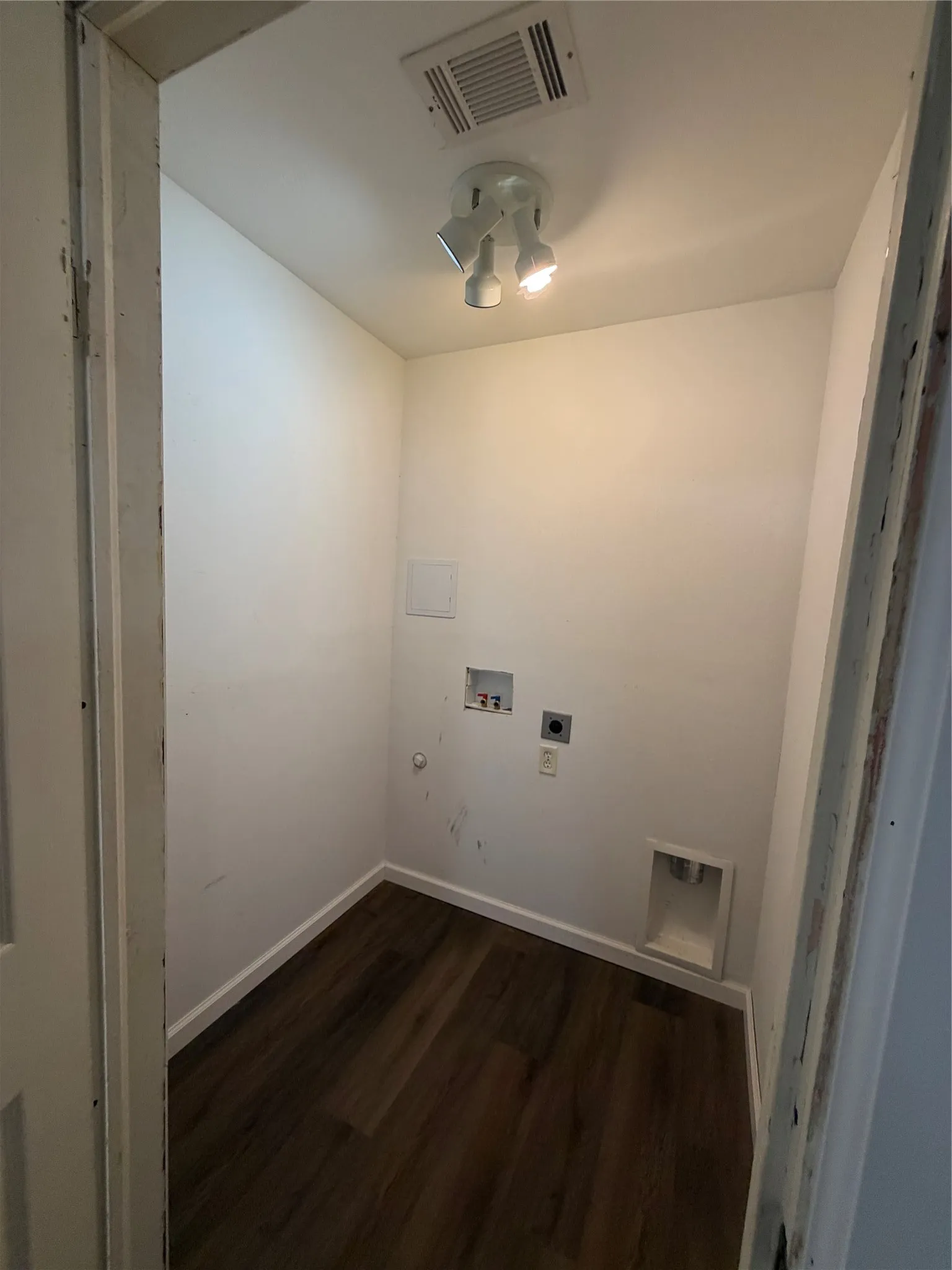 Dedicated utility space featuring wood-finish flooring, white walls, and a ceiling-mounted track light fixture