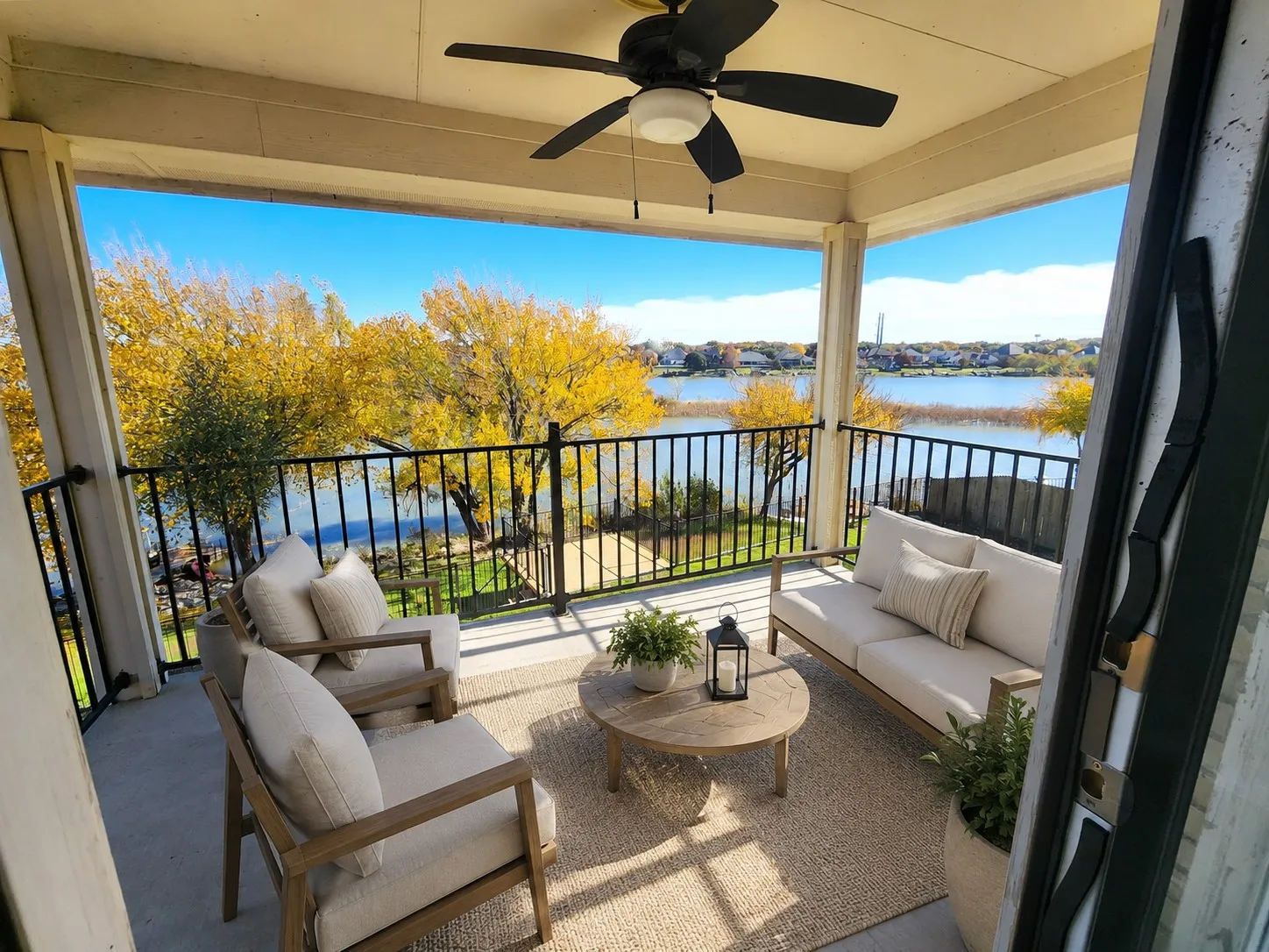 Covered outdoor patio with a ceiling fan, concrete flooring, and black metal railings overlooking a body of water