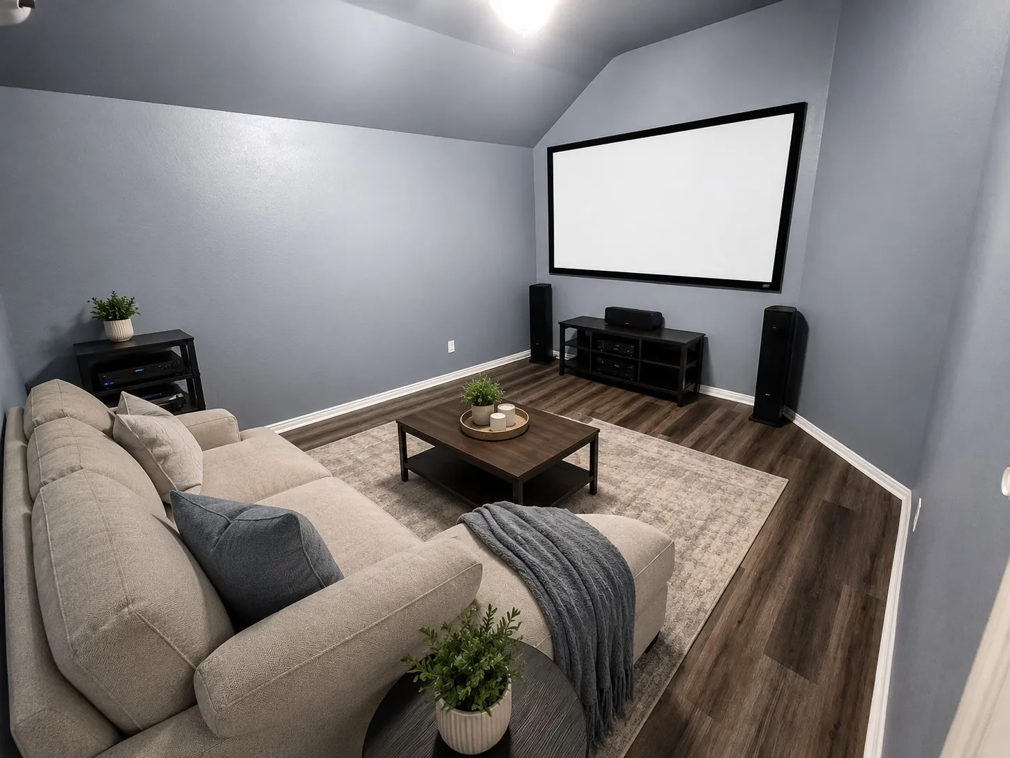 Dedicated media room featuring a large projection screen, plank flooring, and sloped ceiling
