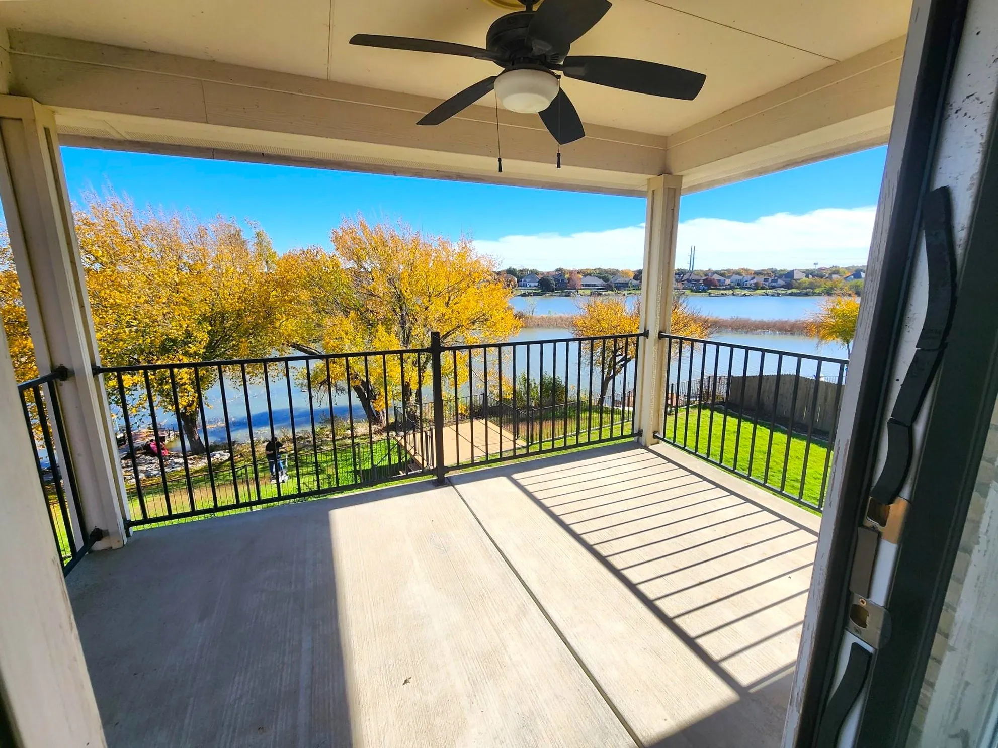 Covered patio with a ceiling fan, concrete flooring, and wrought iron railing overlooking a body of water