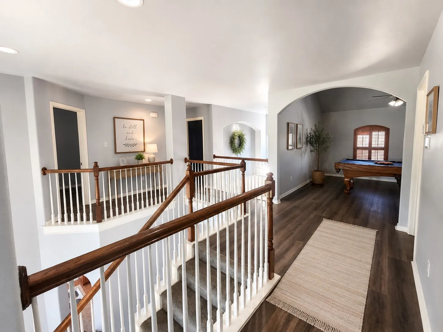 Upper level featuring plank flooring, recessed lighting, arched doorways, and a staircase with wood handrails and white balusters