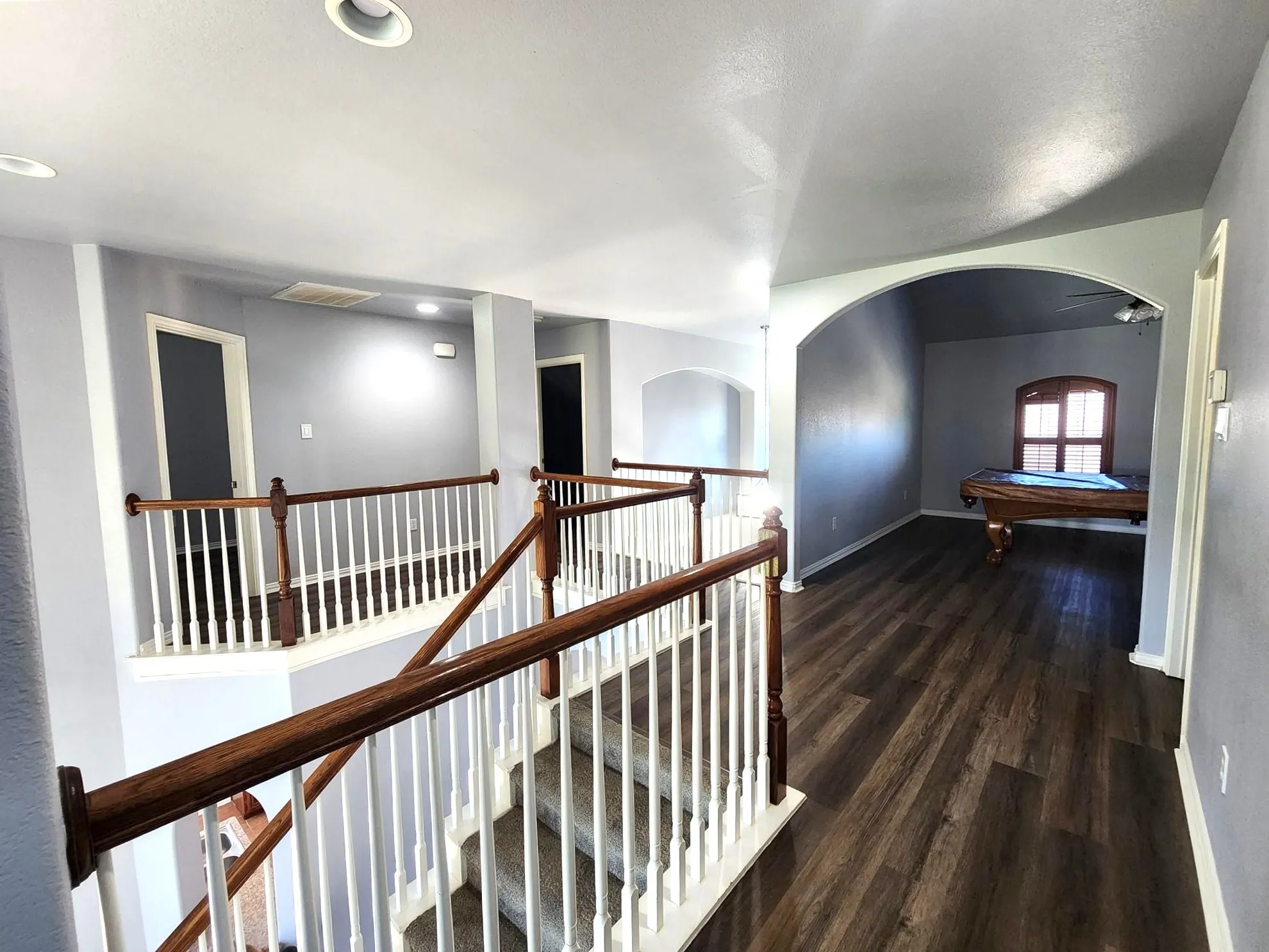 Plank flooring, arched entryway, staircase with wood handrails, recessed lighting, and a ceiling fan